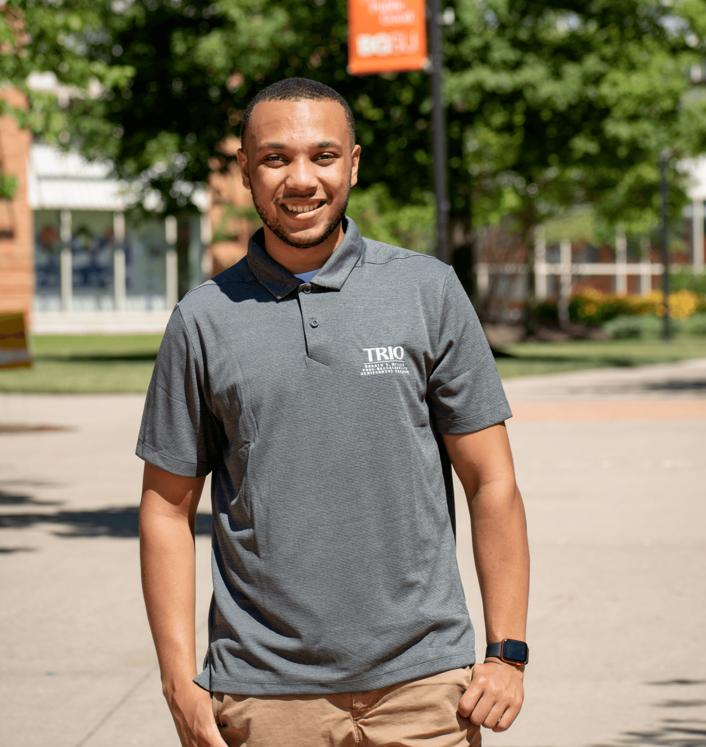 Justin stands centered with a gray polo shirt and khaki pants. 