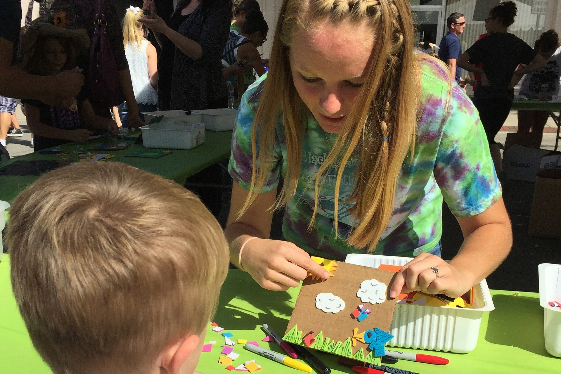 An art education BFA student works on a piece of art with a student outdoors in the Ohio sunshine.