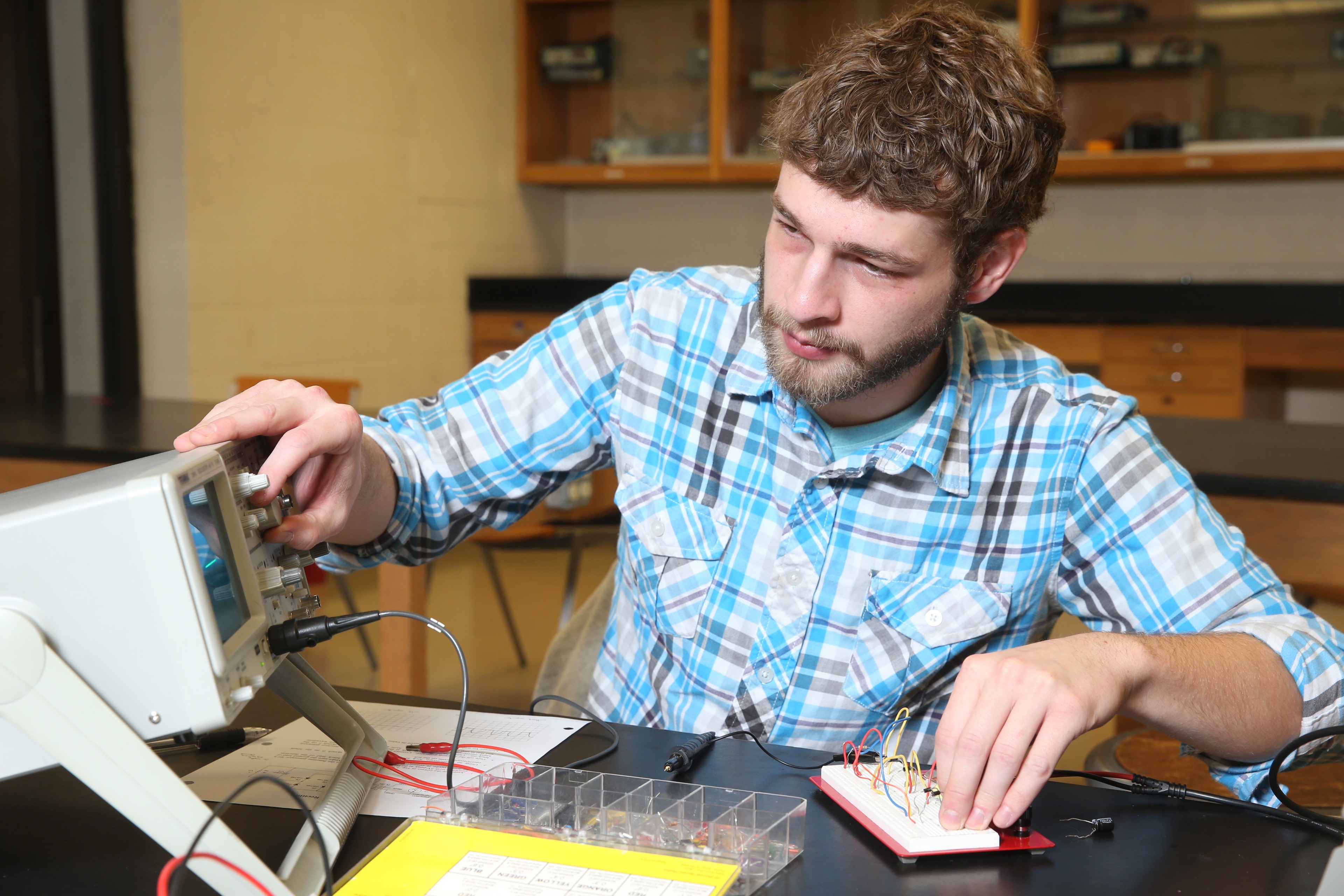 A man sits in an engineering lab working 