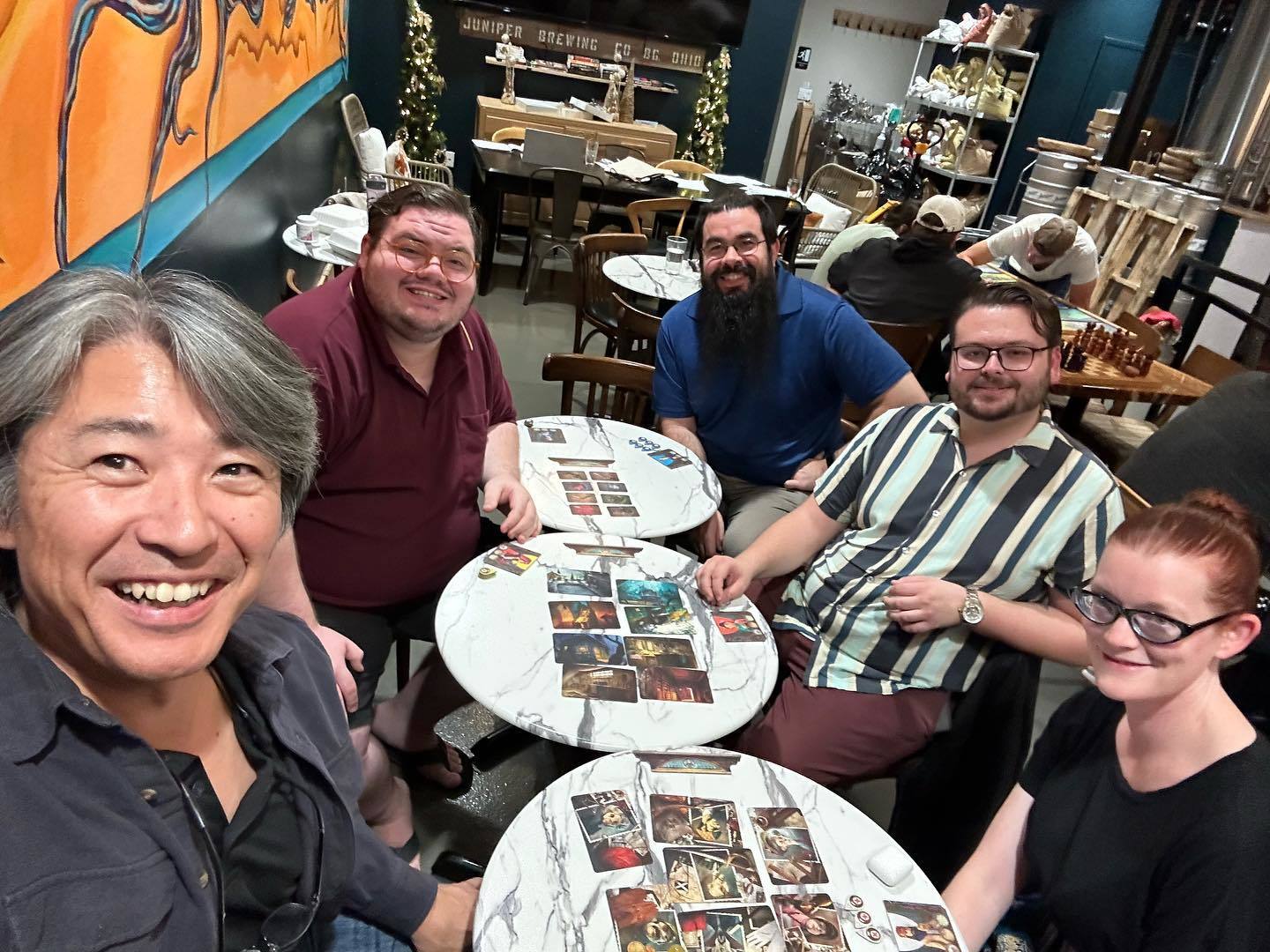 A photo of Paul Kei Matsuda playing board games at Juniper with English Department graduate students. Left to right: Paul Kei Matsuda, TJ Pyatt, Bryan Urias, William Walton-Case, Charity Givens.