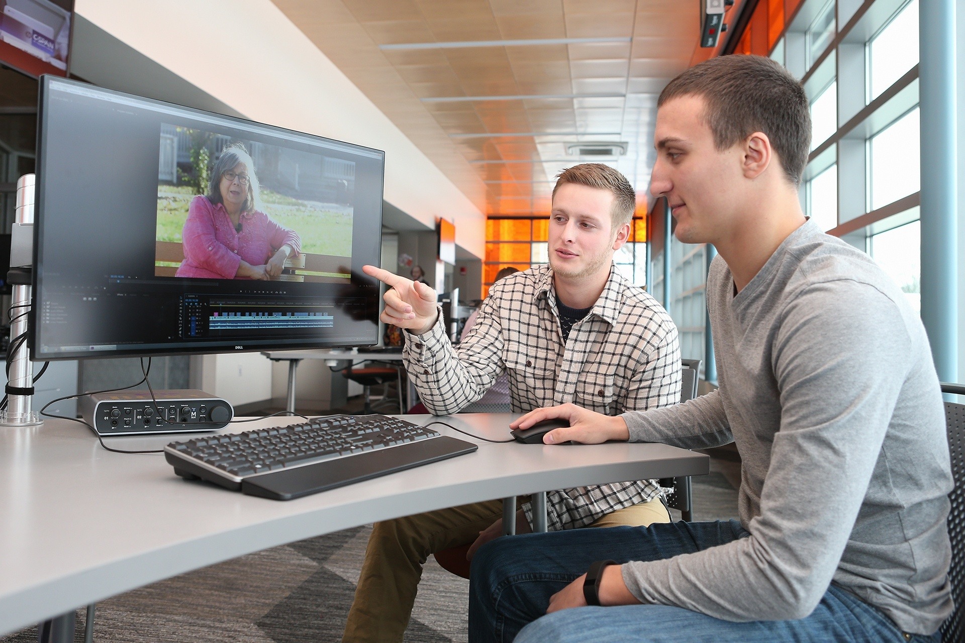 Two BGSU media production and studies majors work on a computer to create a video story in the BGSU Convergence Studio.