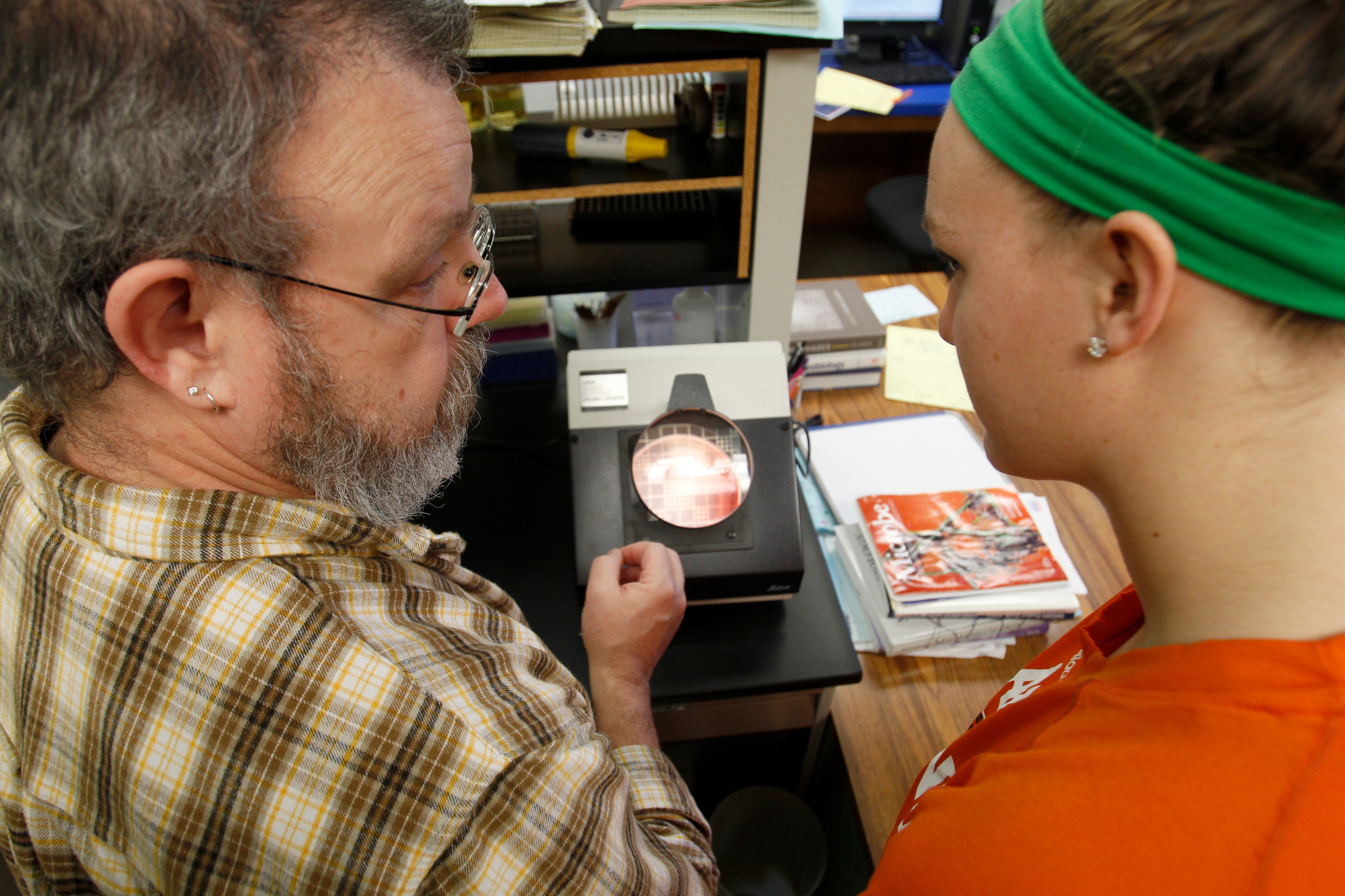 Professor and student working together over a microscope