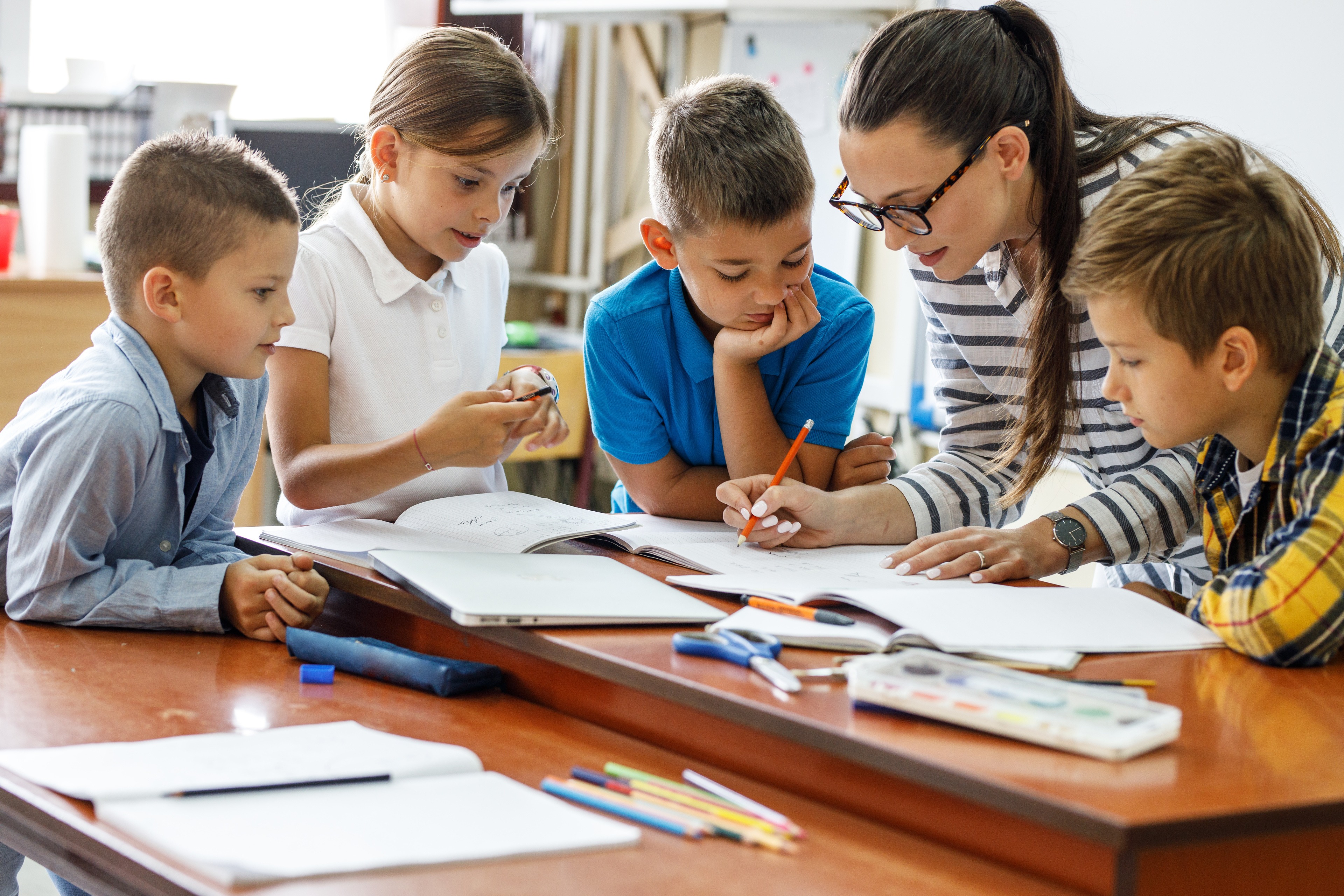 A kind female teacher spends time with her elementary school students, making learning enjoyable and fun while sparking curiosity and fostering a love for education.