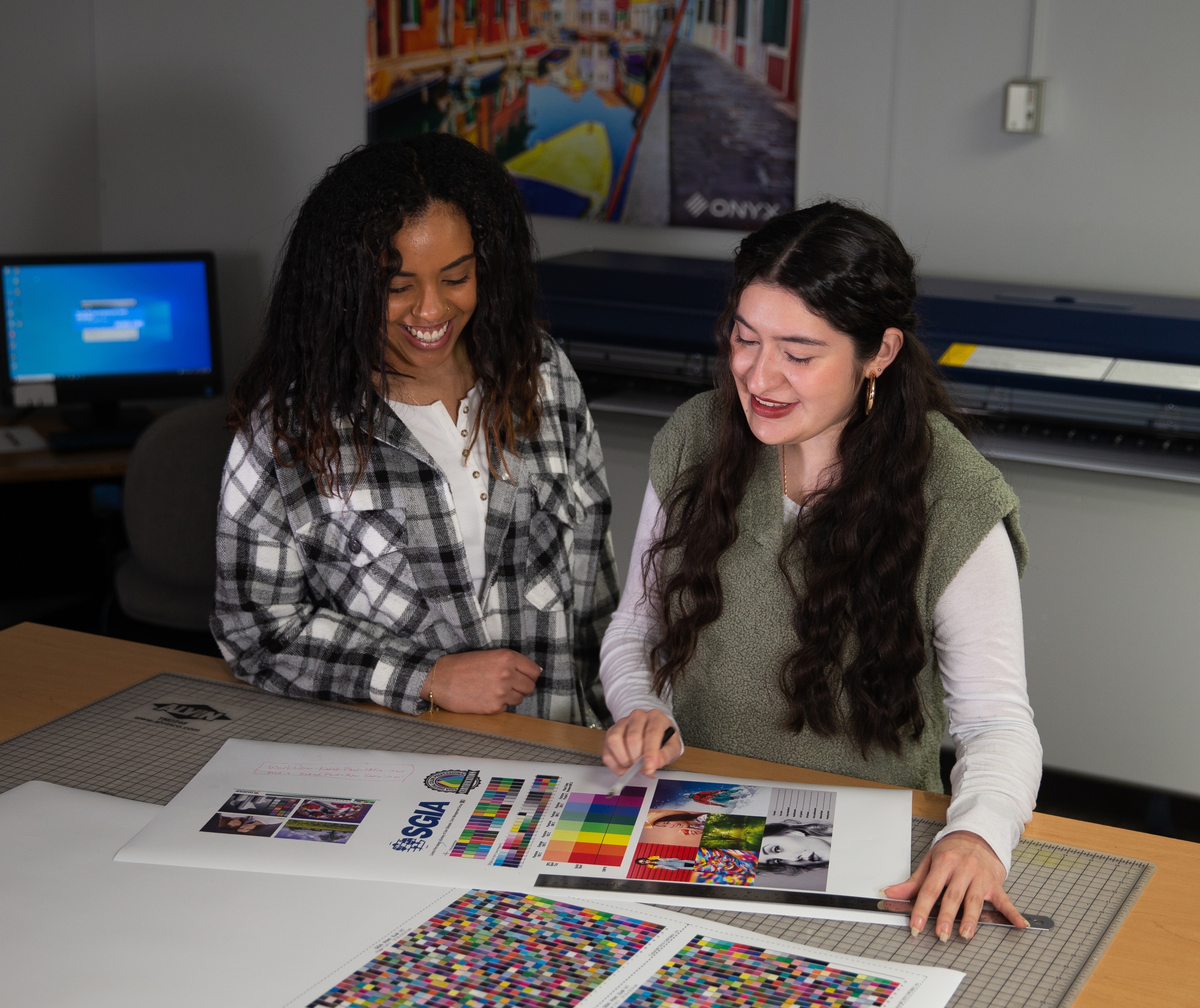 Two female visual communication technology majors at BGSU look at a color chart for a project they’re working on