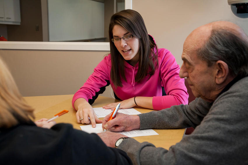 A female social worker works on paperwork with an elderly man.