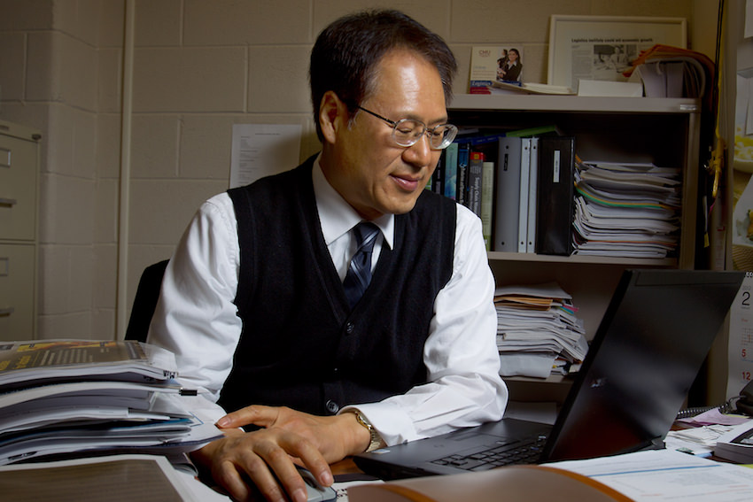 Dr. Hokey Min at a desk looking down at his laptop while working
