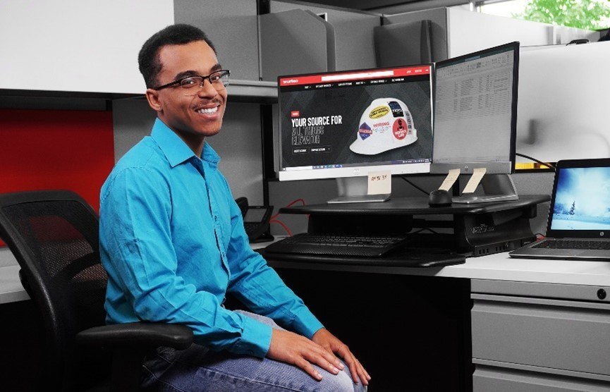 Jalin Trevion Golden sitting front of a computer in an office cubicle 