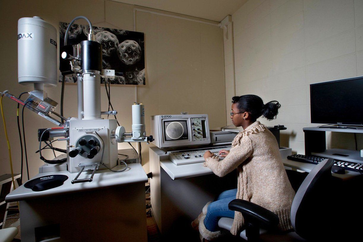 A student seated at the console of the scanning electron microscope