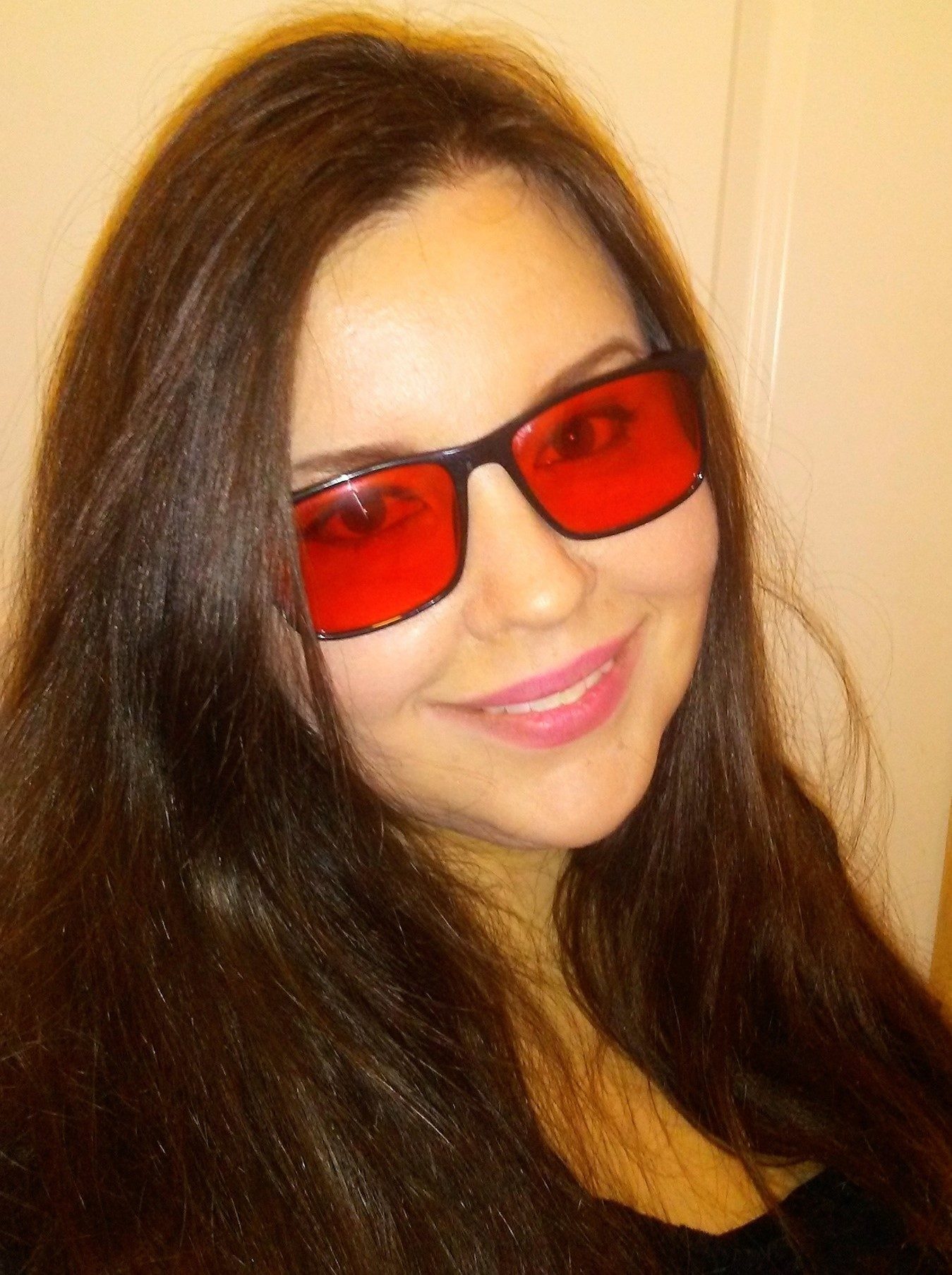 a picture of Charity Anderson, a smiling woman with long dark hair who is also wearing blue-light-blocking prescription glasses to avoid a migraine