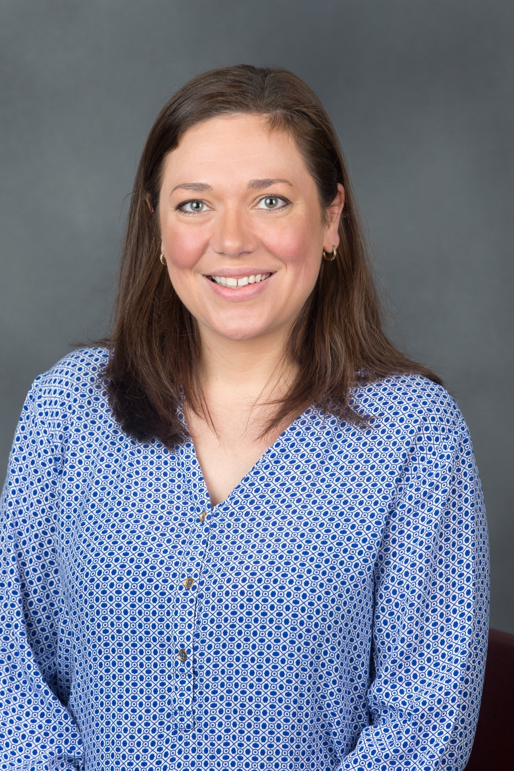 Professional headshot of Alexia Coffman wearing a blue and white blouse