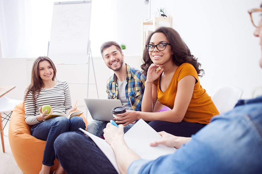 A group of two females and two males sitting and having a conversation with one another.