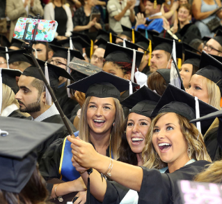 Angelica Mormile, right, takes a selfie with her friends as they celebrate August Commencement at The Stroh Center.
