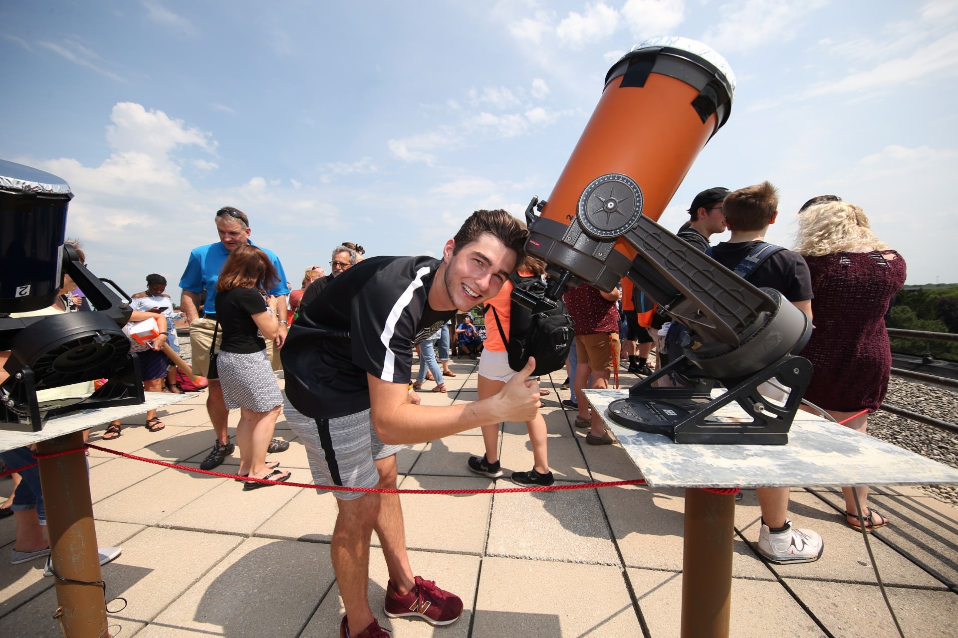  guy smiling at camera next to telescope