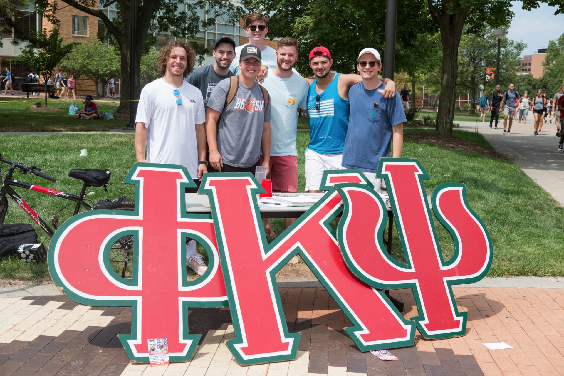 Group of fraternity members standing together behind letters sign