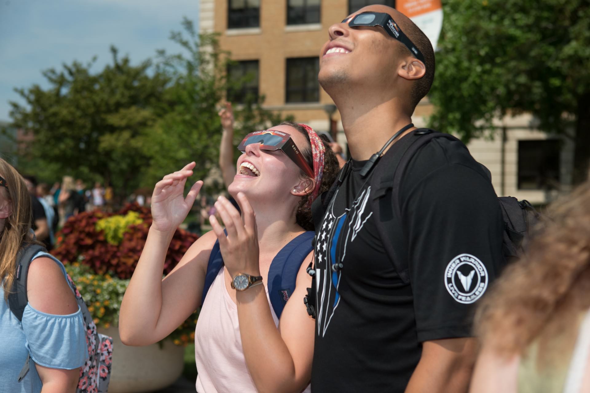 Two students looking up at sky wearing solar eclipse glasses
