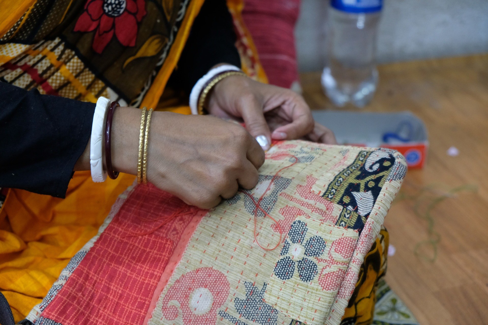 Hands of a woman rescued from trafficking sewing a bag in Kantha