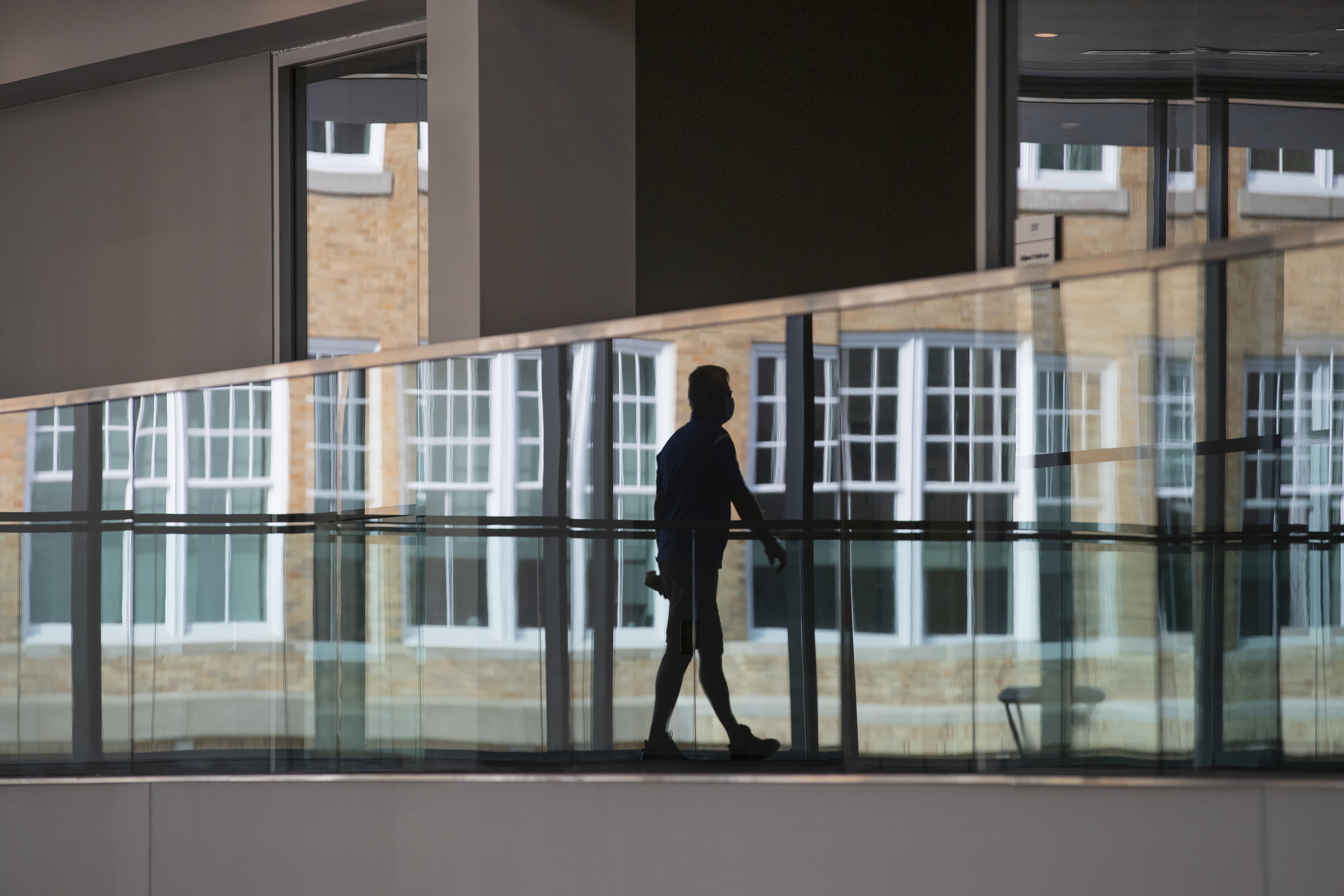 A Schmidthorst College of Business faculty member is reflected in the balcony glass as he walks through the Maurer Center.