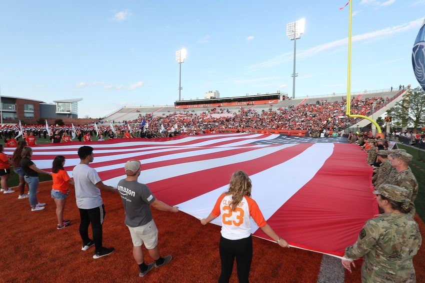 group of students on field holding american flag