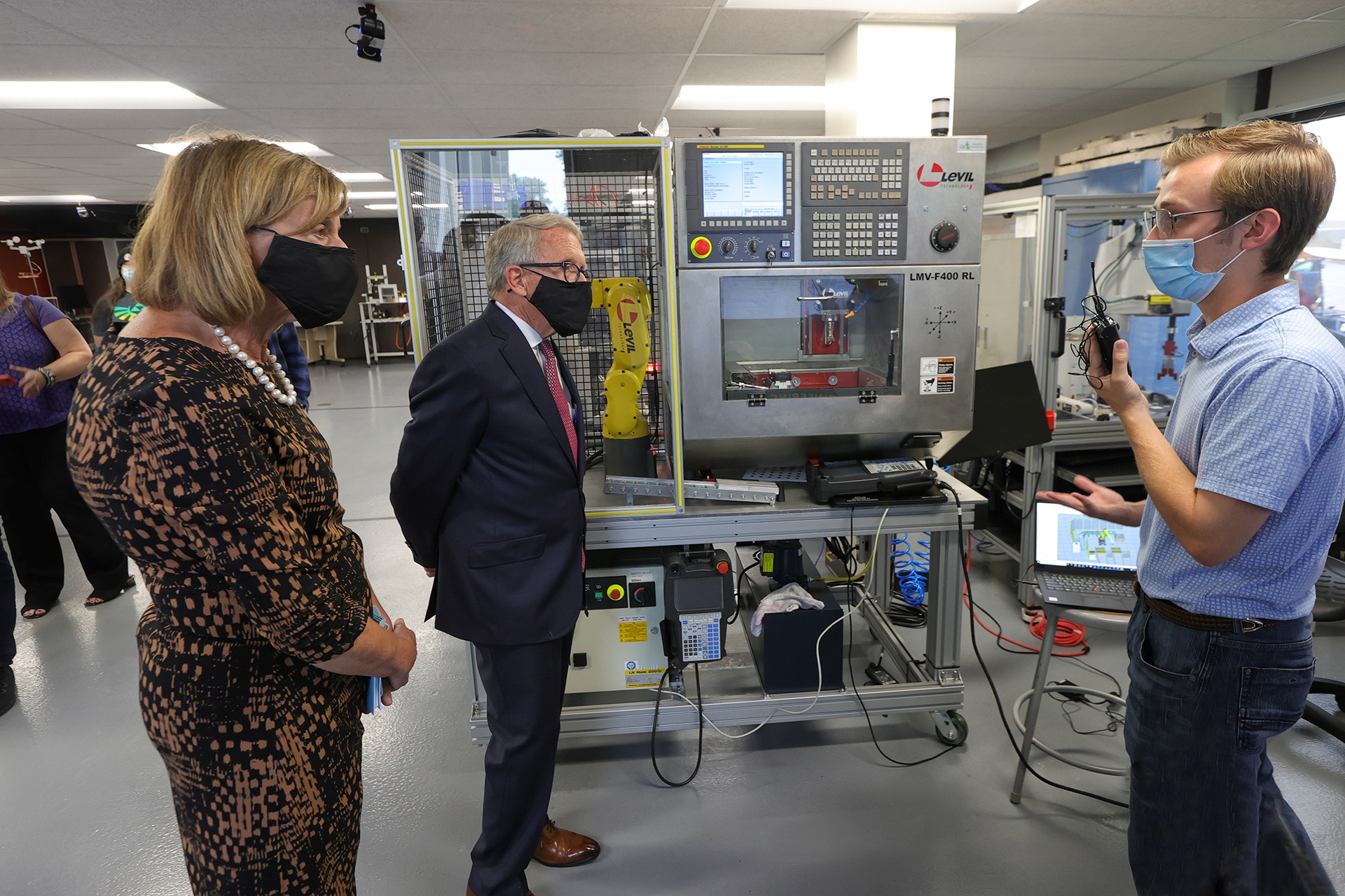 Ian Kennedy speaking to Governor Mike DeWine and Fran DeWine in a robotics laboratory