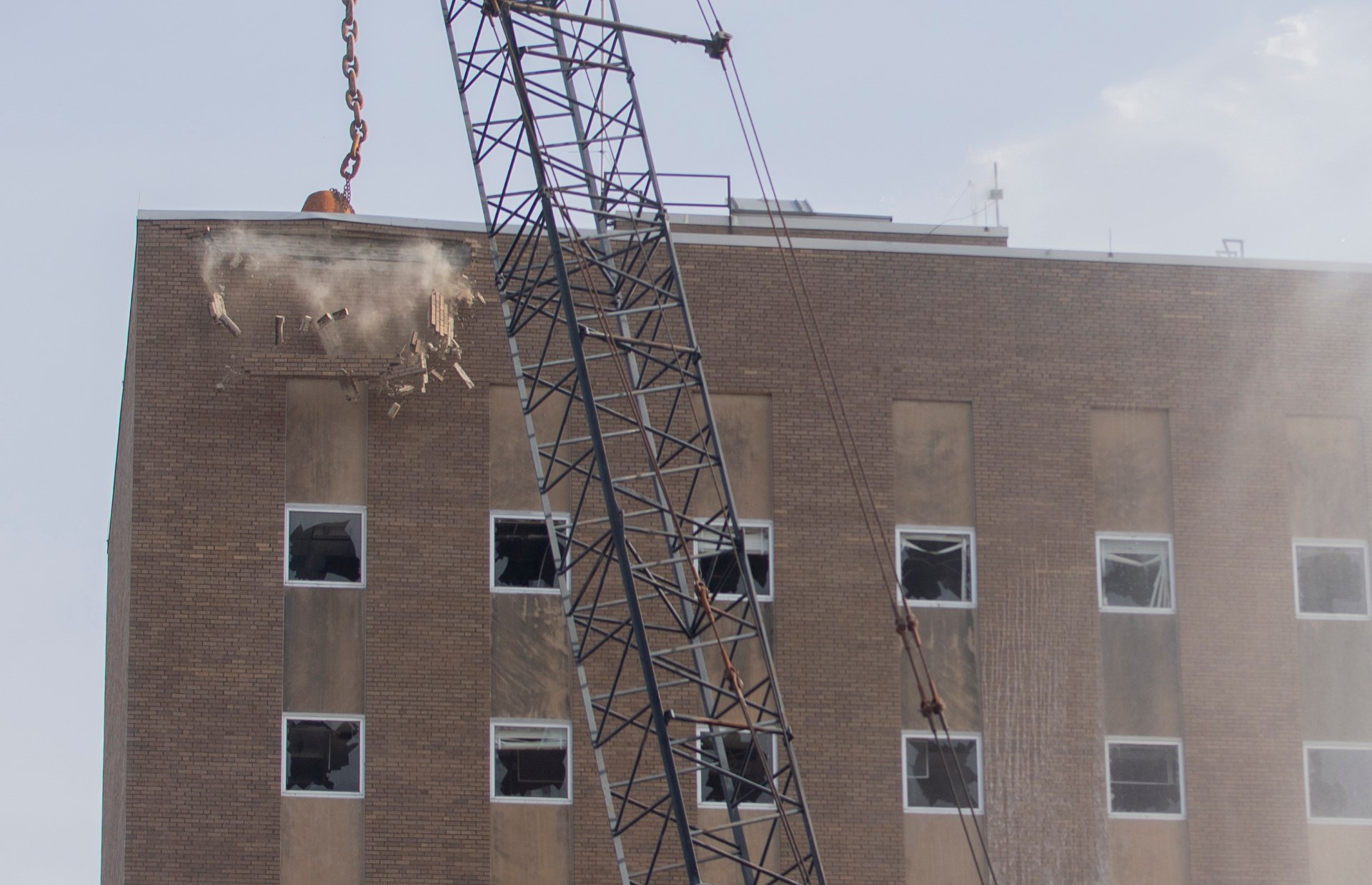 a wrecking ball hitting the top left corner of the building and bricks falling