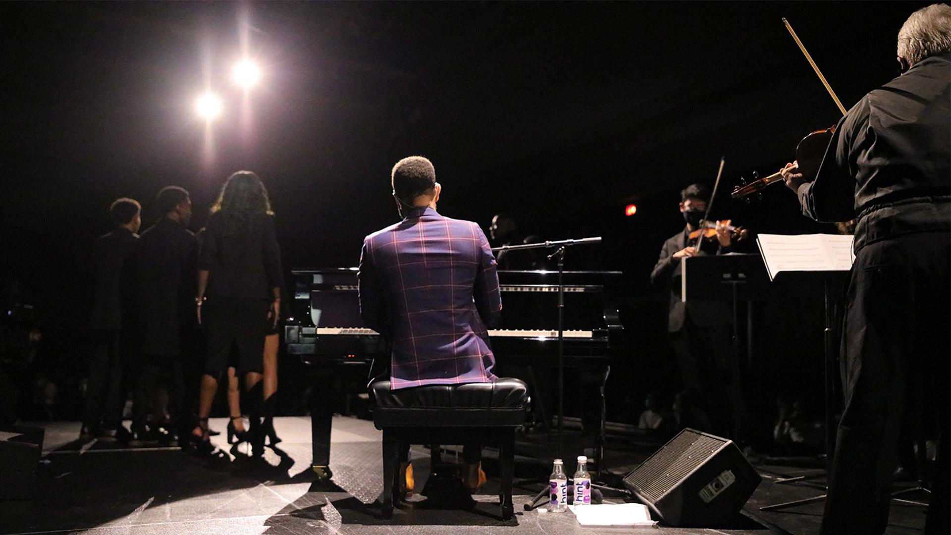 John Legend playing the piano while Voices at BG sings at the concert