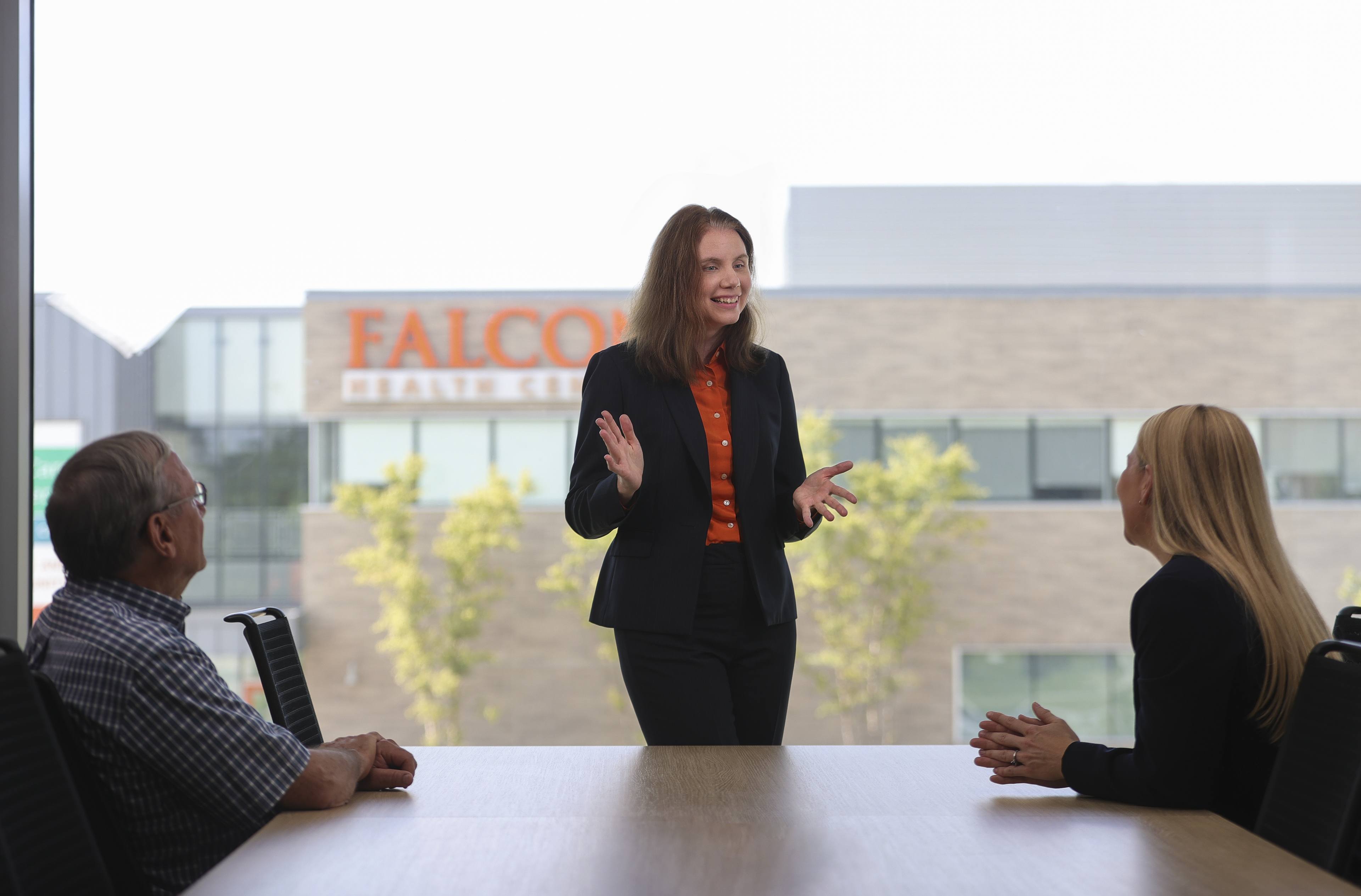 Jennifer Percival speaking to two people sitting at a table