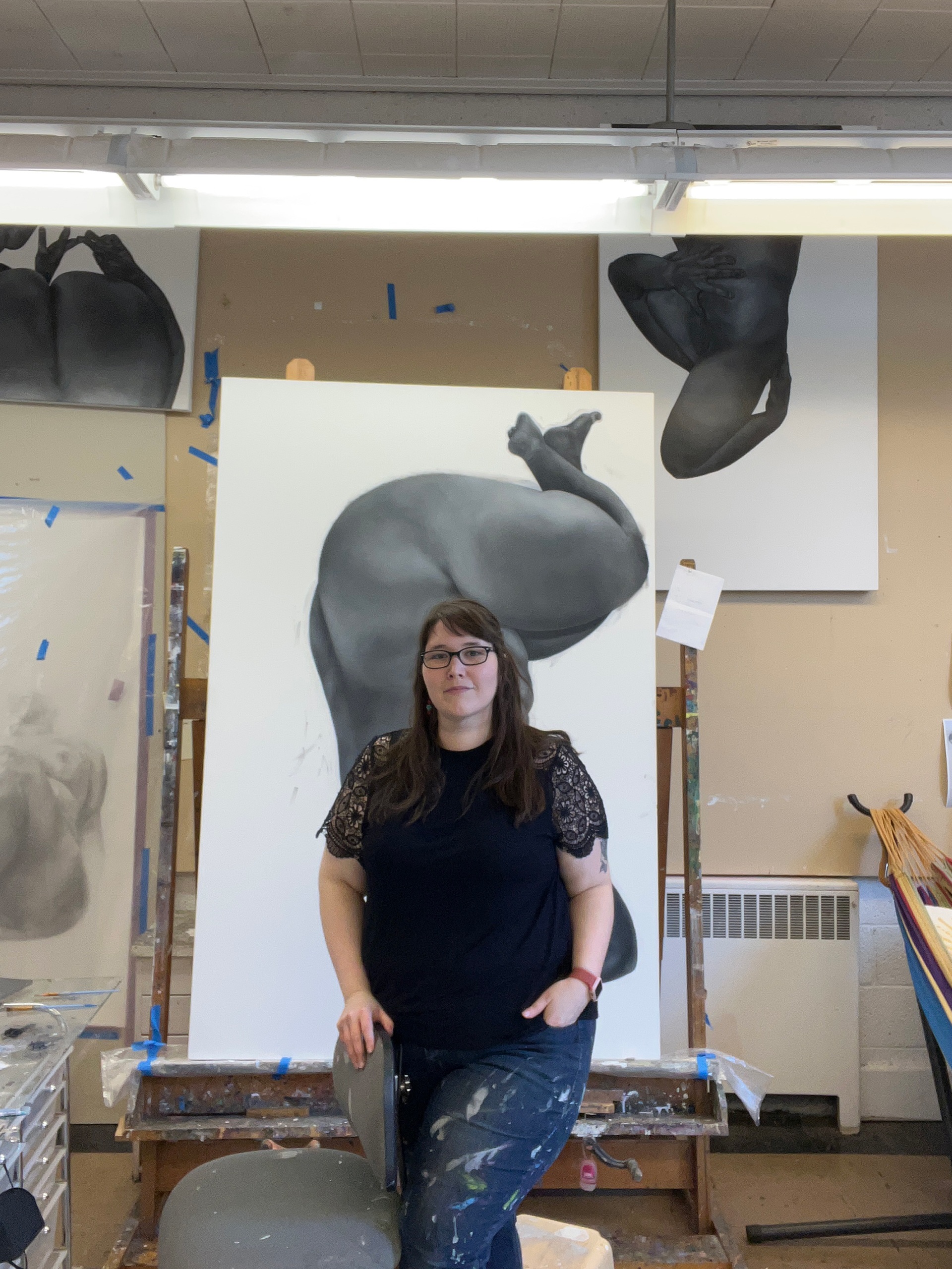 Crystalyn Hutchens standing in front of one of her paintings