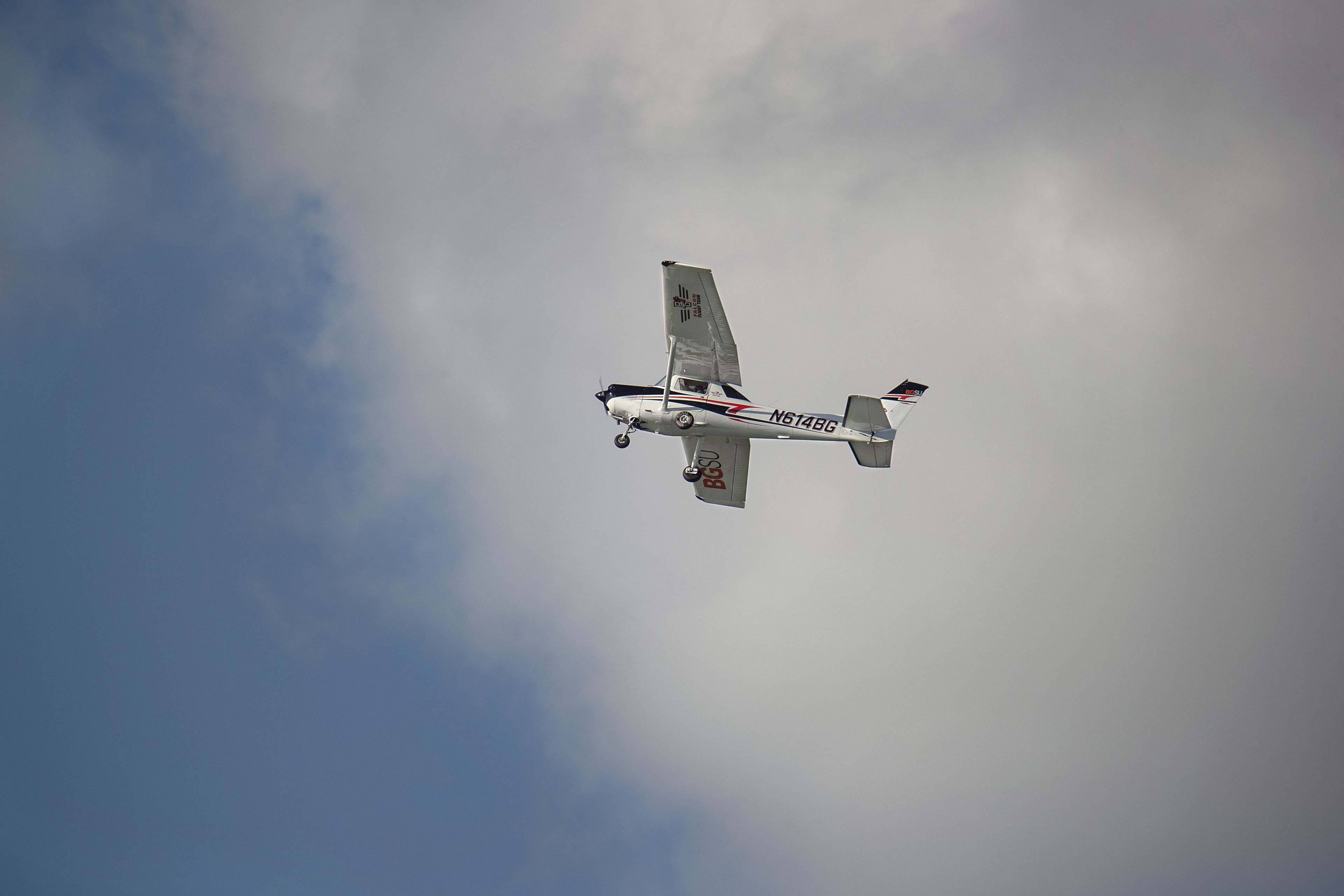 Plane flying overhead in front of clouds and blue sky