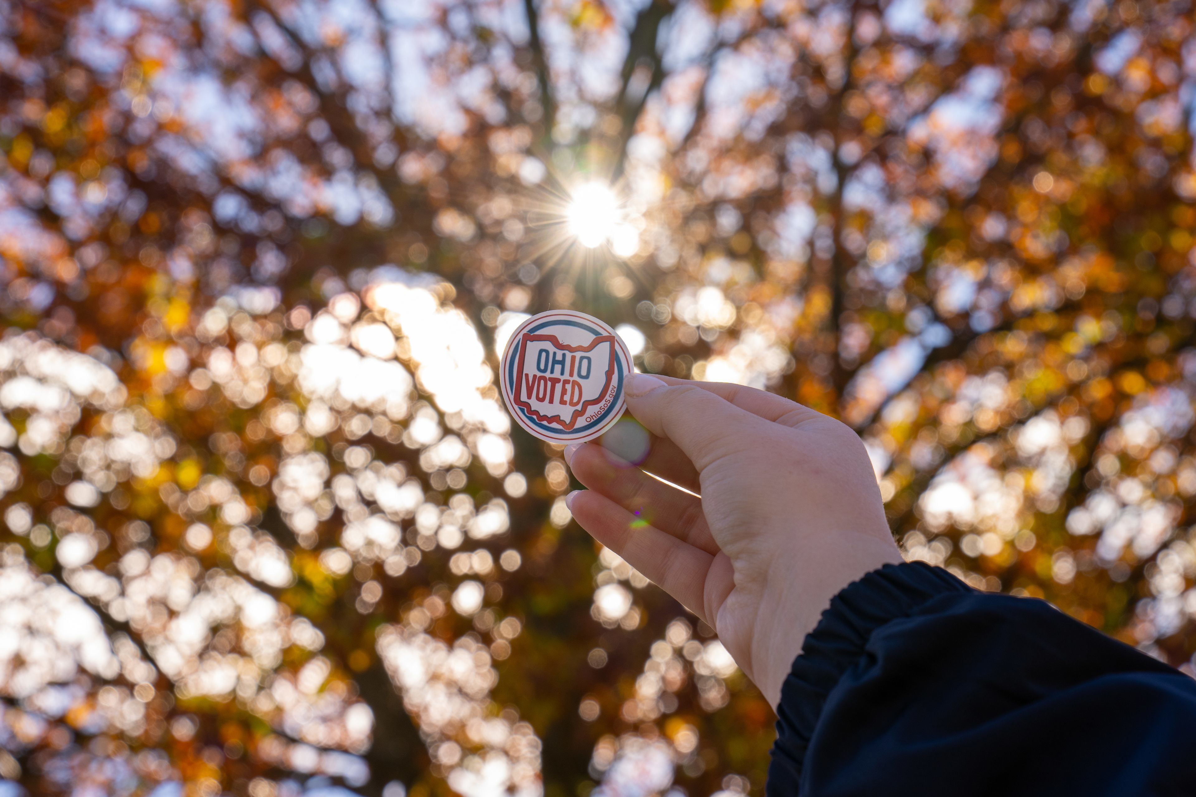 A hand holding an Ohio "I Voted" sticker 