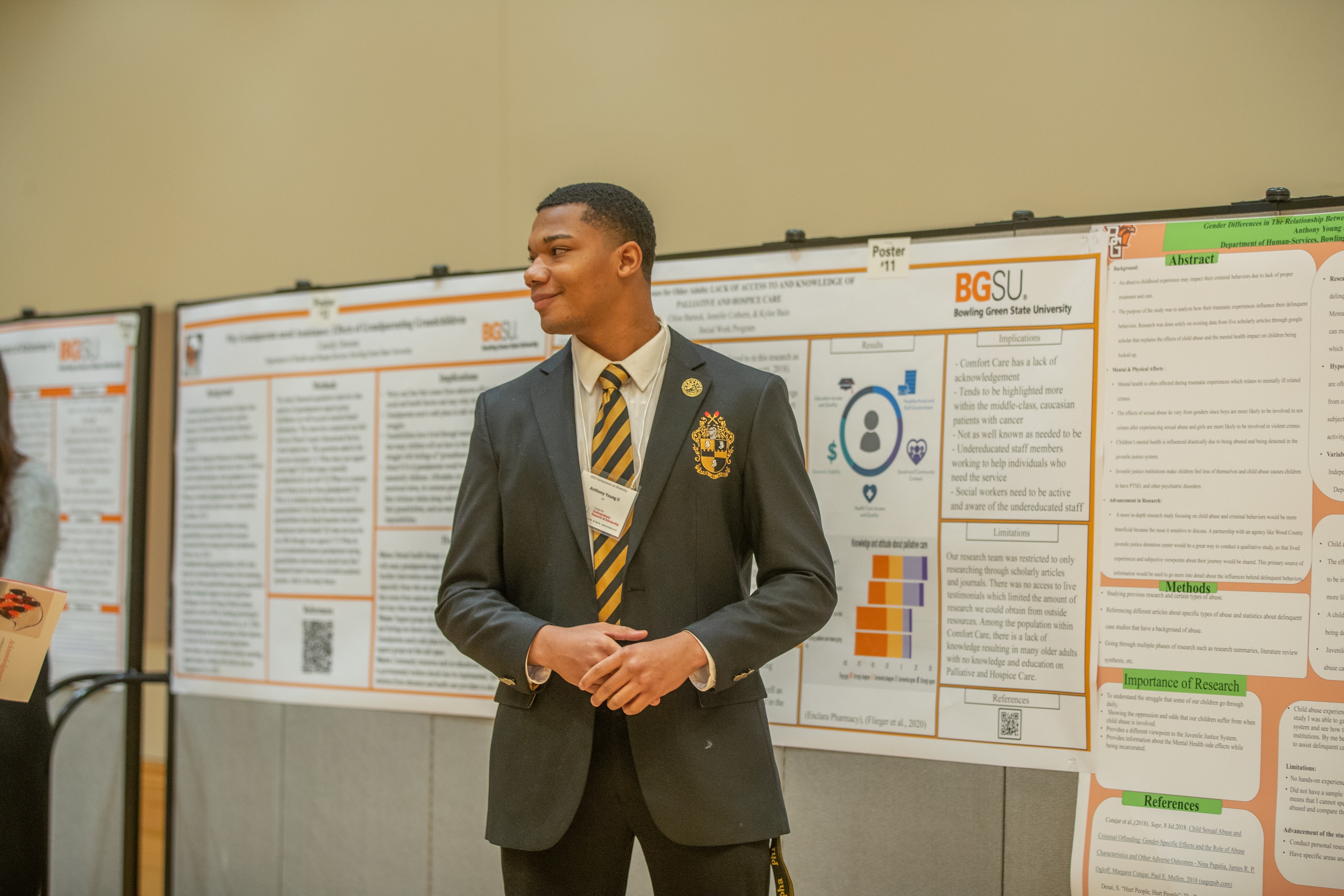 A student stands in front of poster presentations