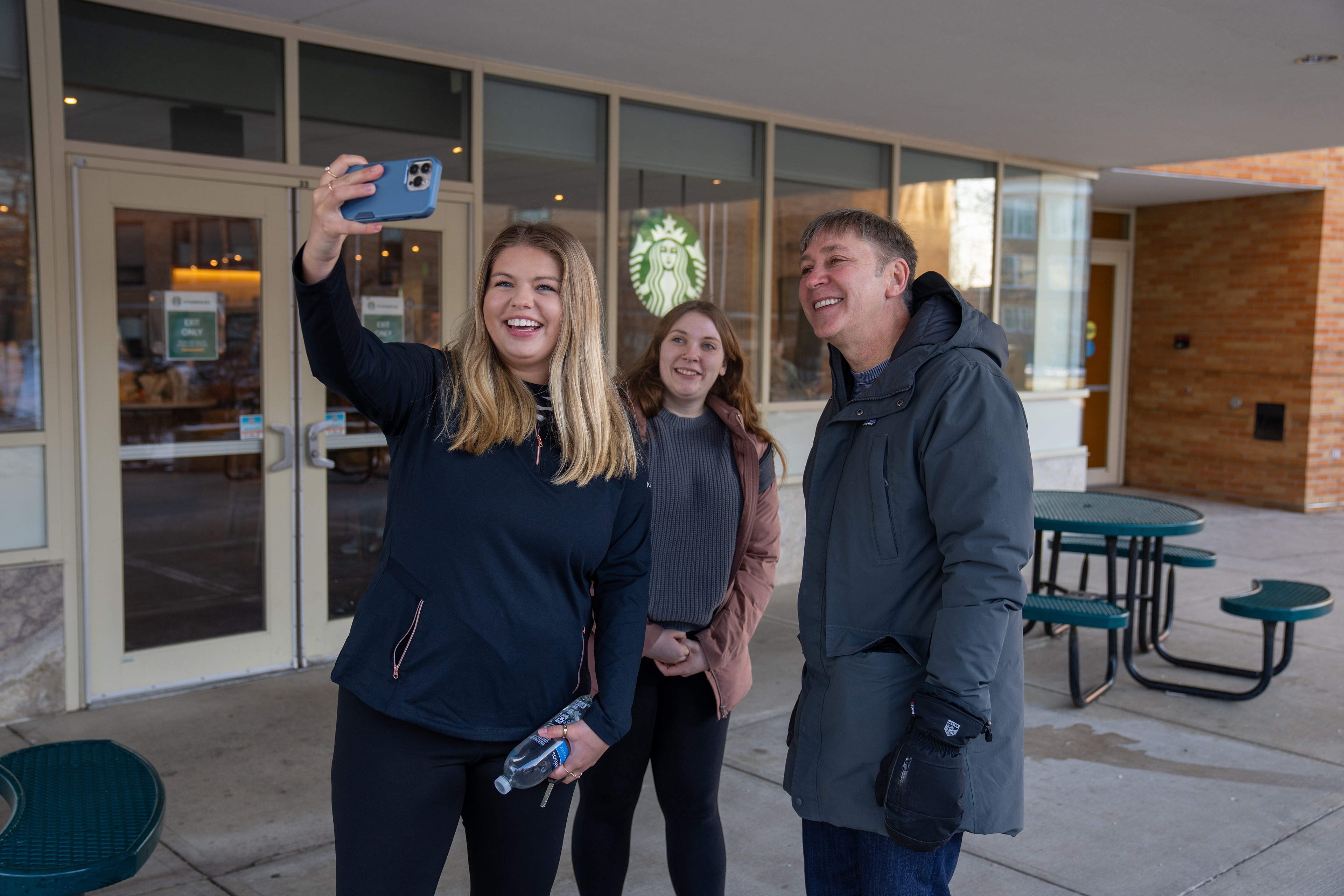 Two students take photos with BGSU alumnus Steve Hartman