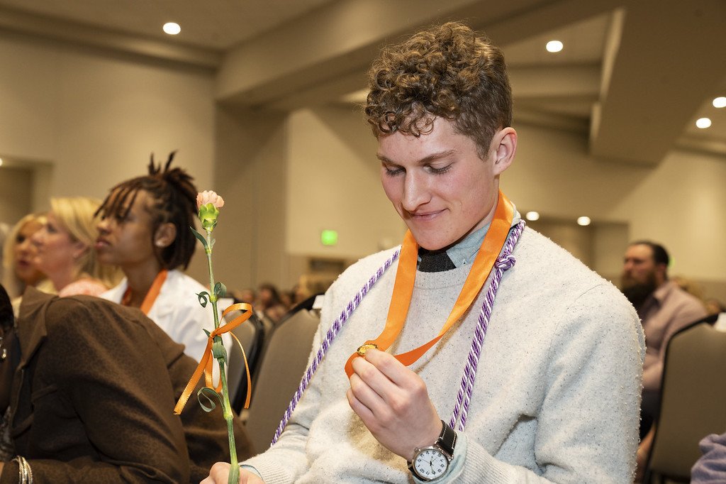 Alex Johnson admiring his pin at the BSN pinning ceremony