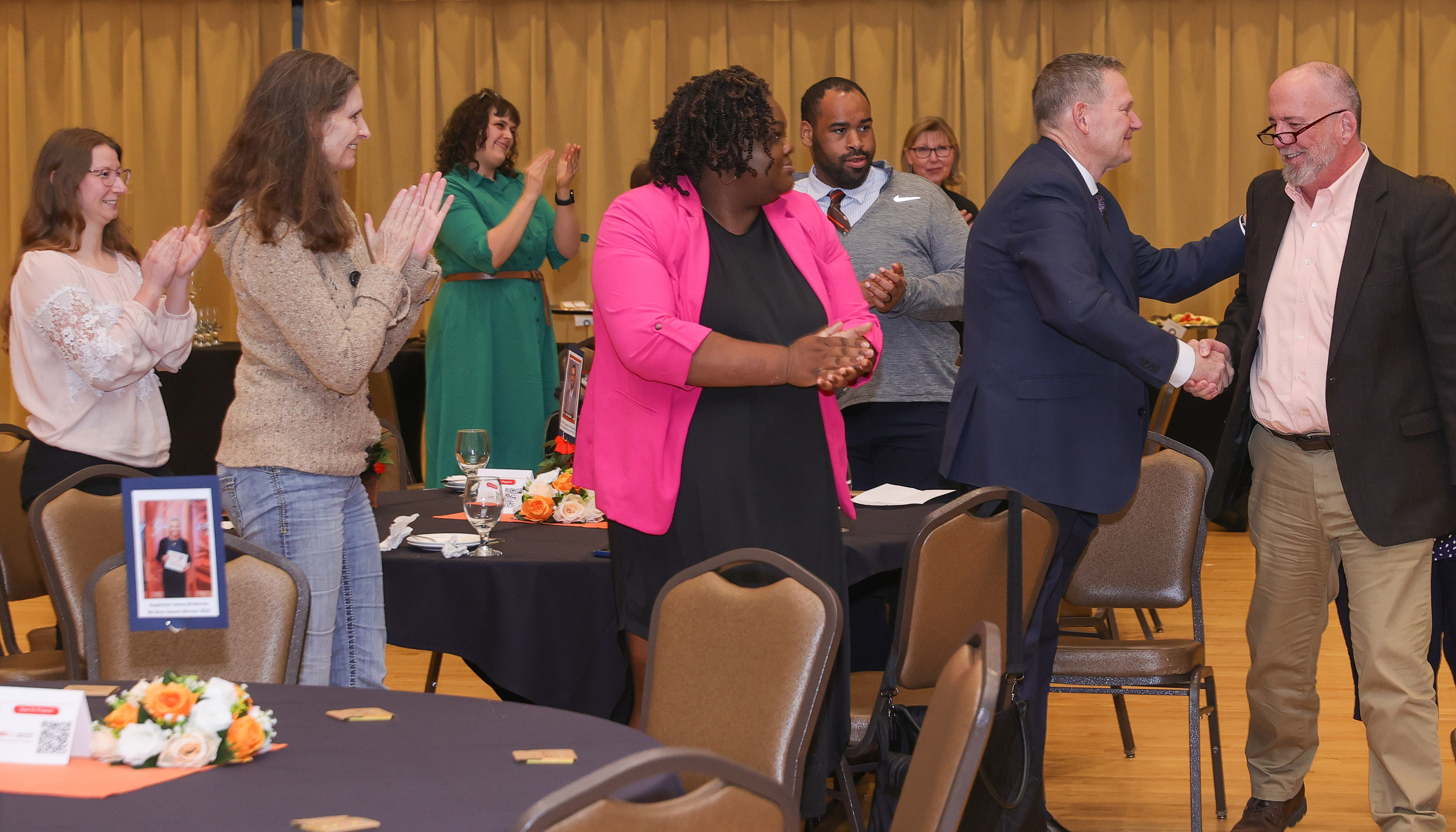 Six people stand and applaud award winner Tom Gorman