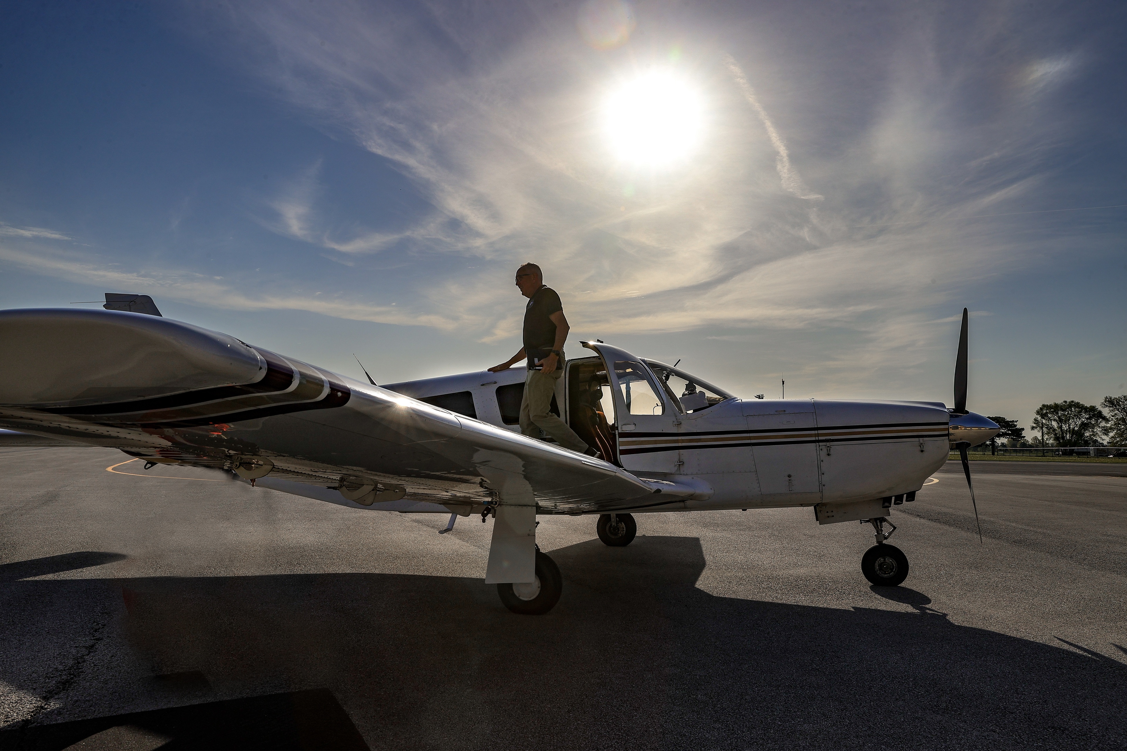 Man exits airplane and stands on wing.