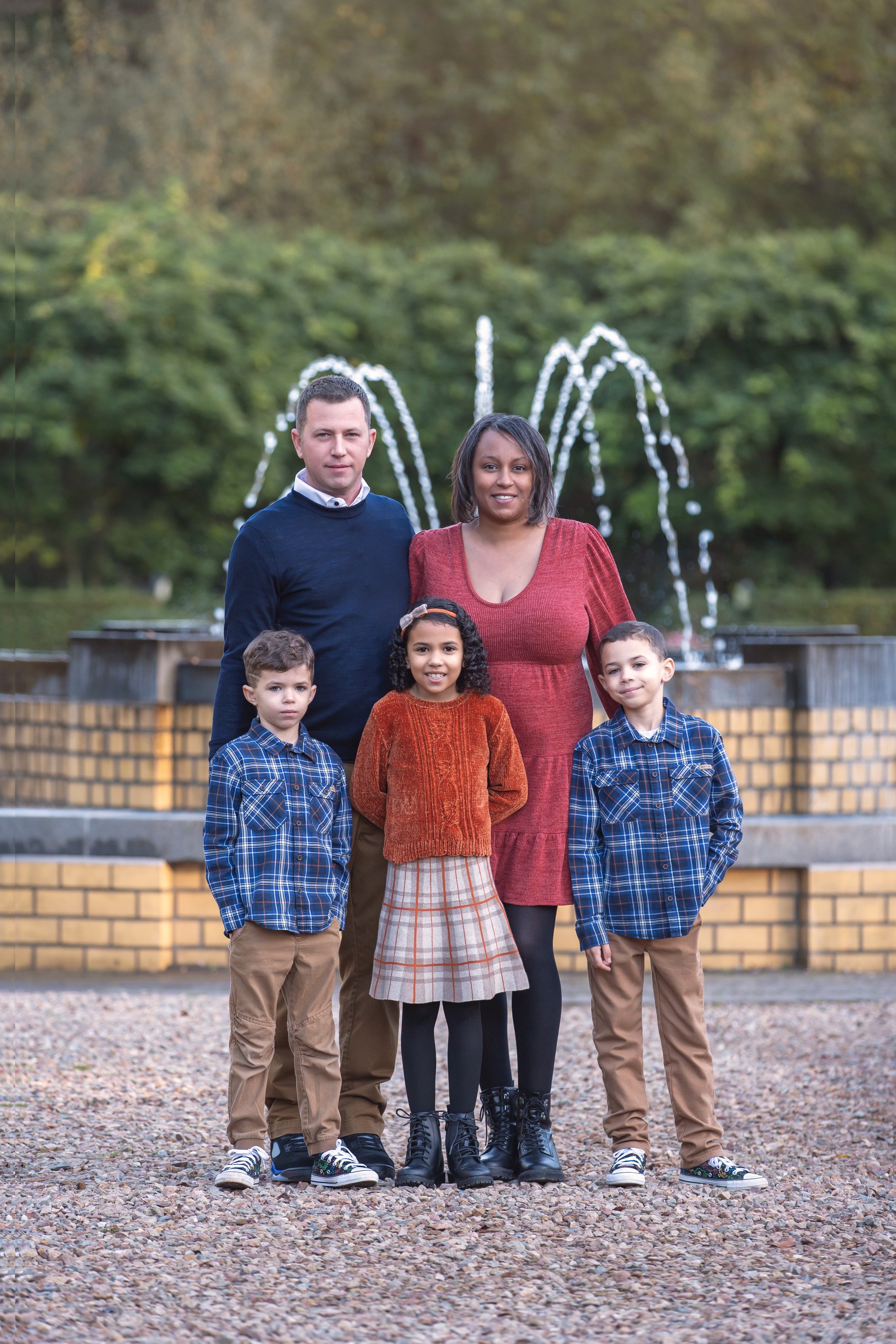 Family stands in front of a fountain.