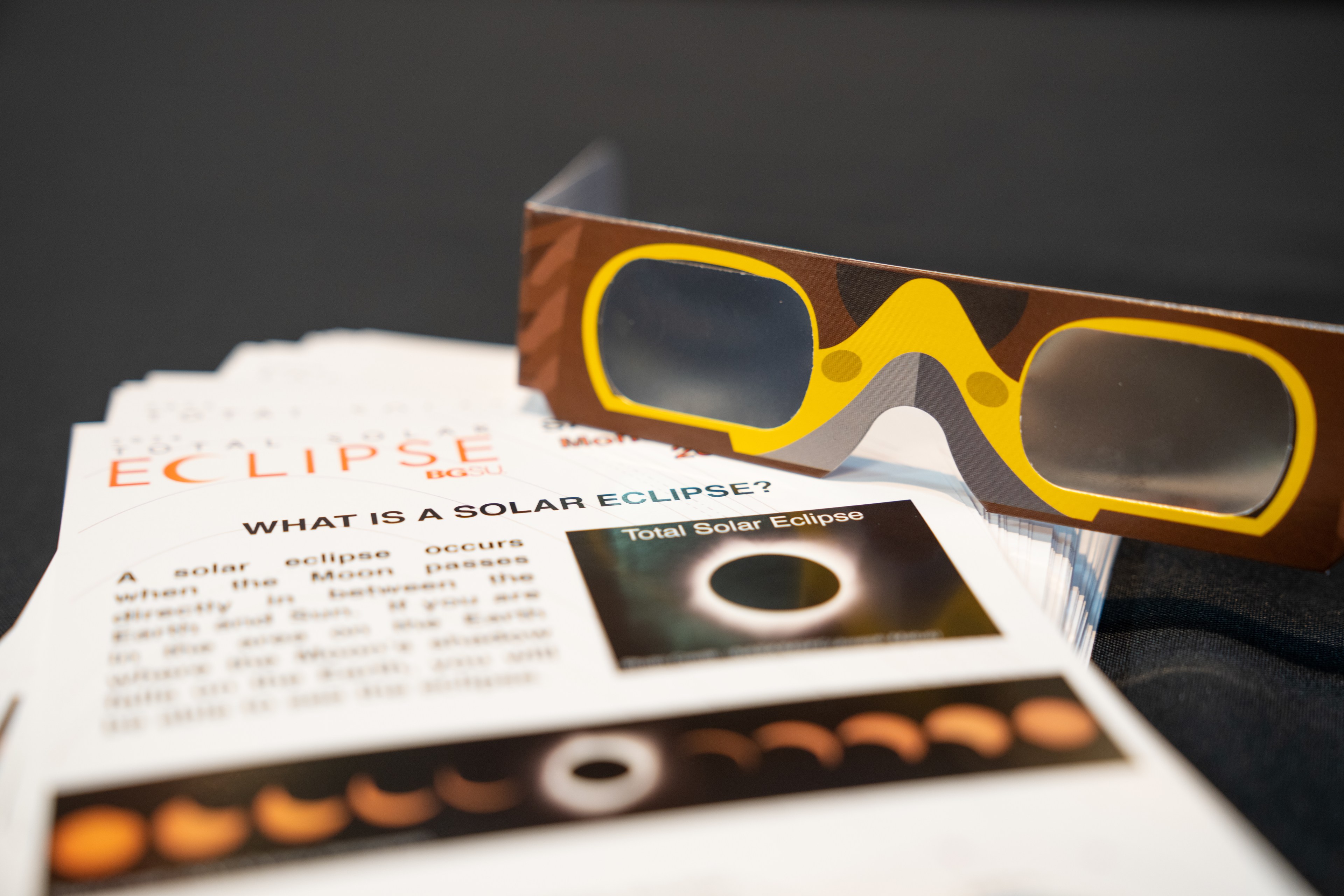 Paper handouts show information about the total solar eclipse and safe eclipse viewing glasses