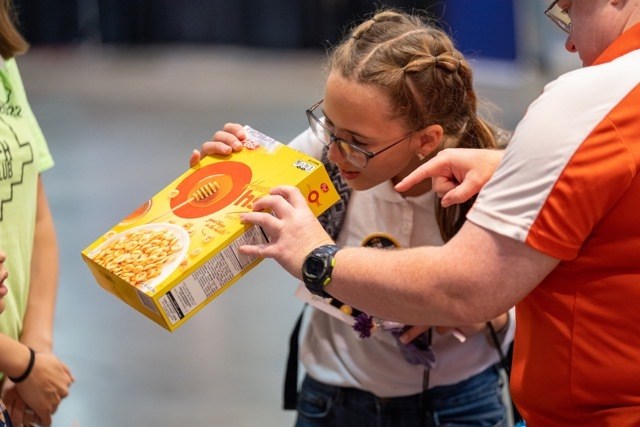Girl looks at a cereal box that is turned into a solar eclipse projector