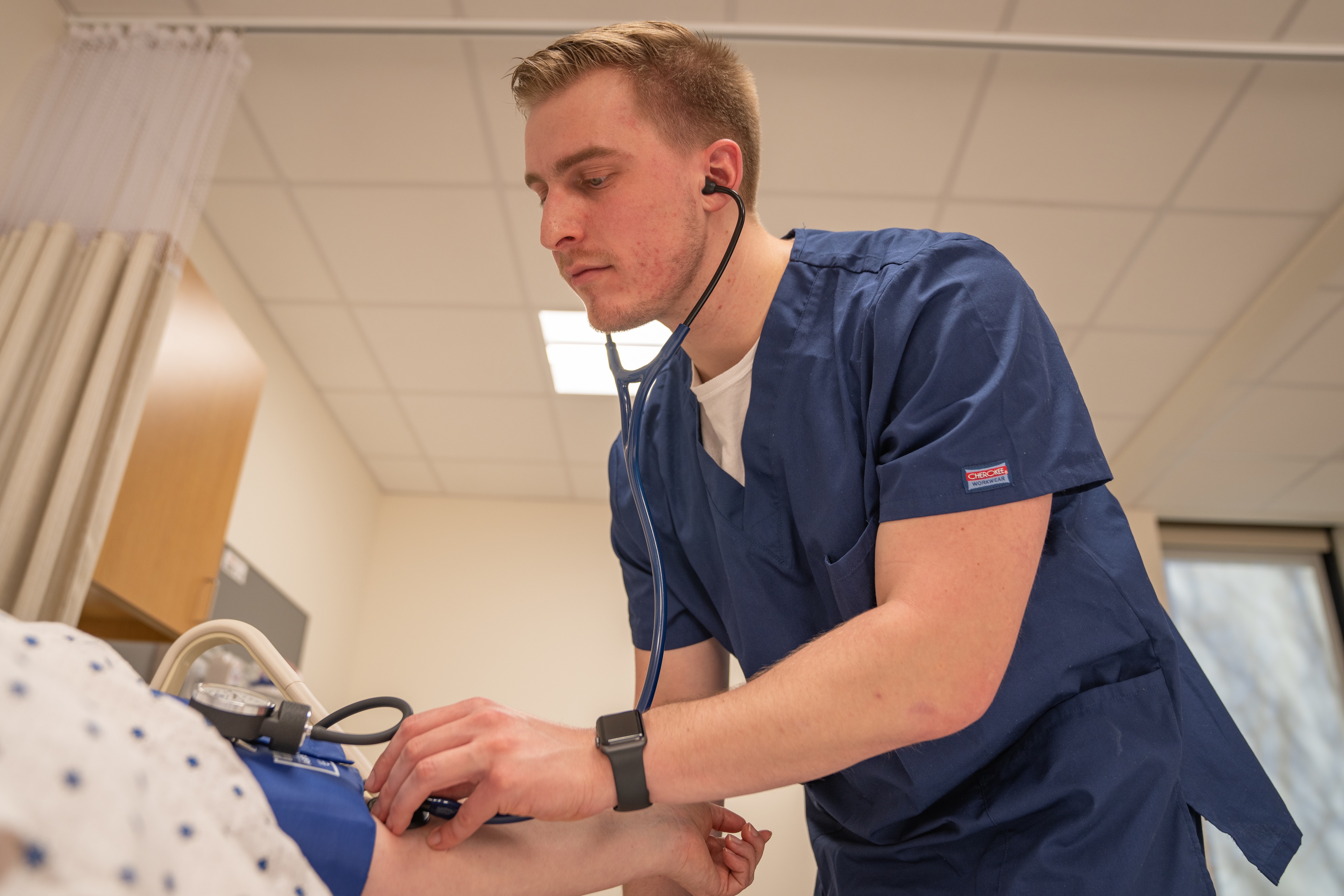 Nursing student checking patient's blood pressure