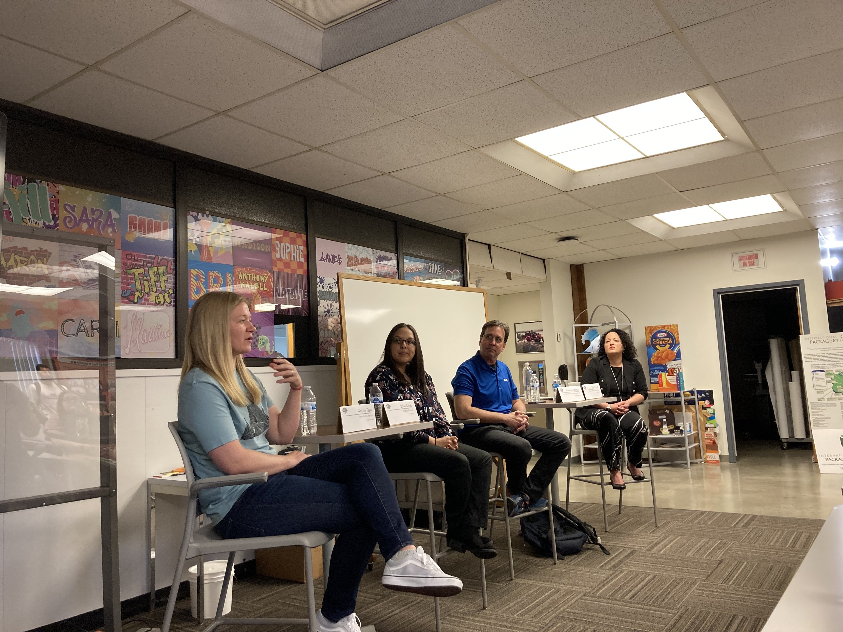 A group of people sitting in chairs at the front of a classroom.