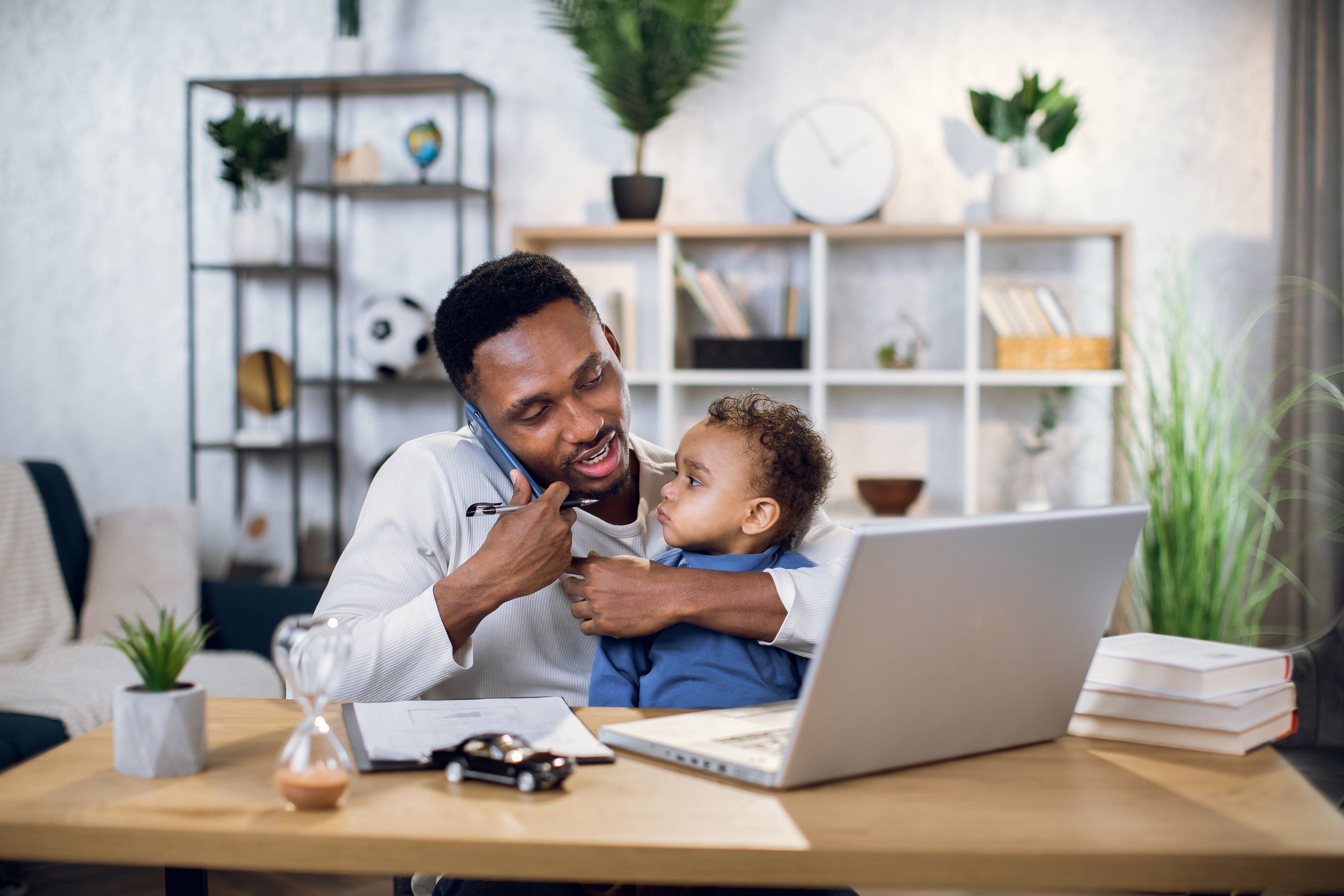 A person holding a baby while talking on a cell phone. 