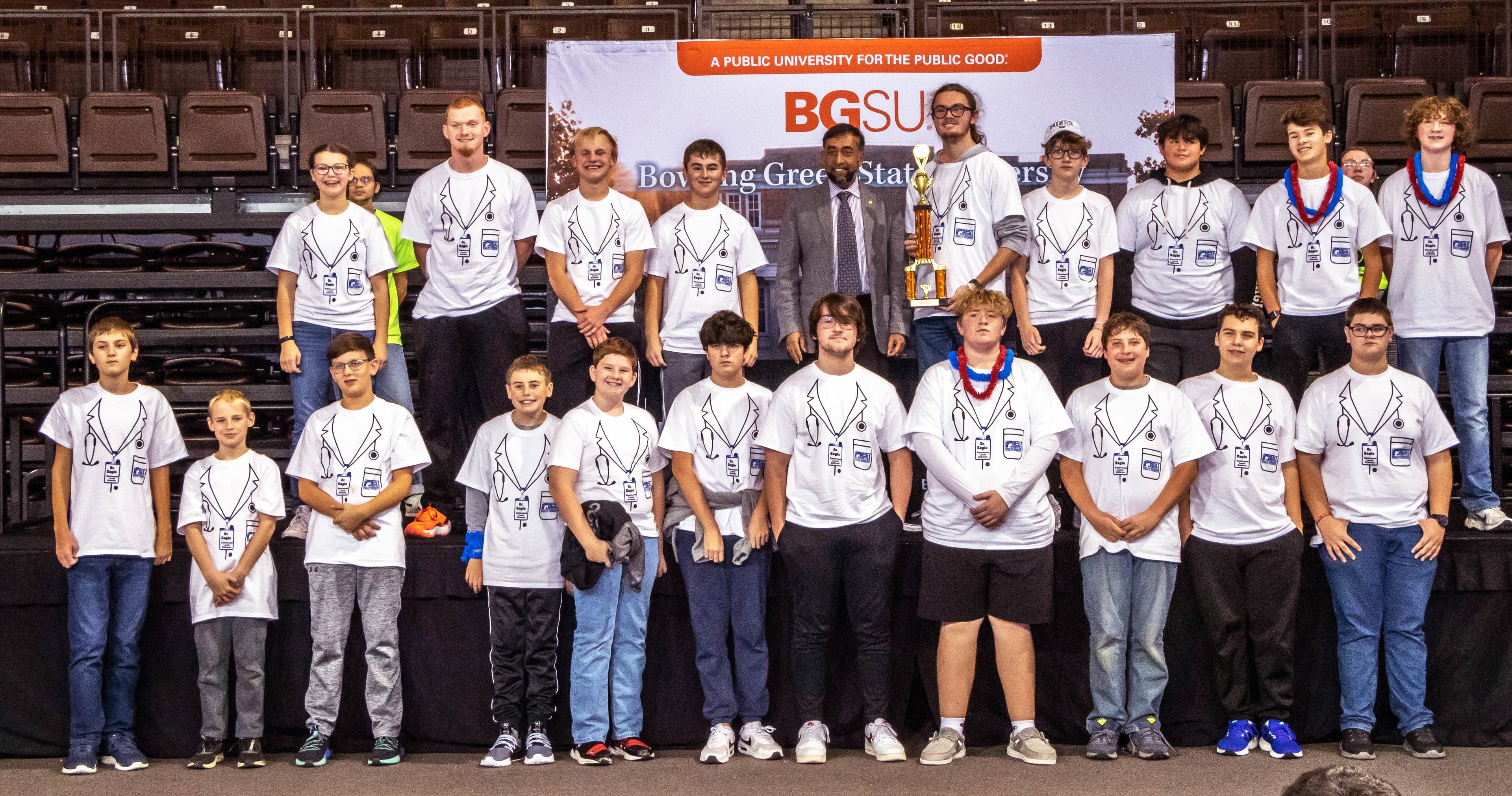 A large group of high school students pose on a stage with Dr. MD Sarder of BGSU.