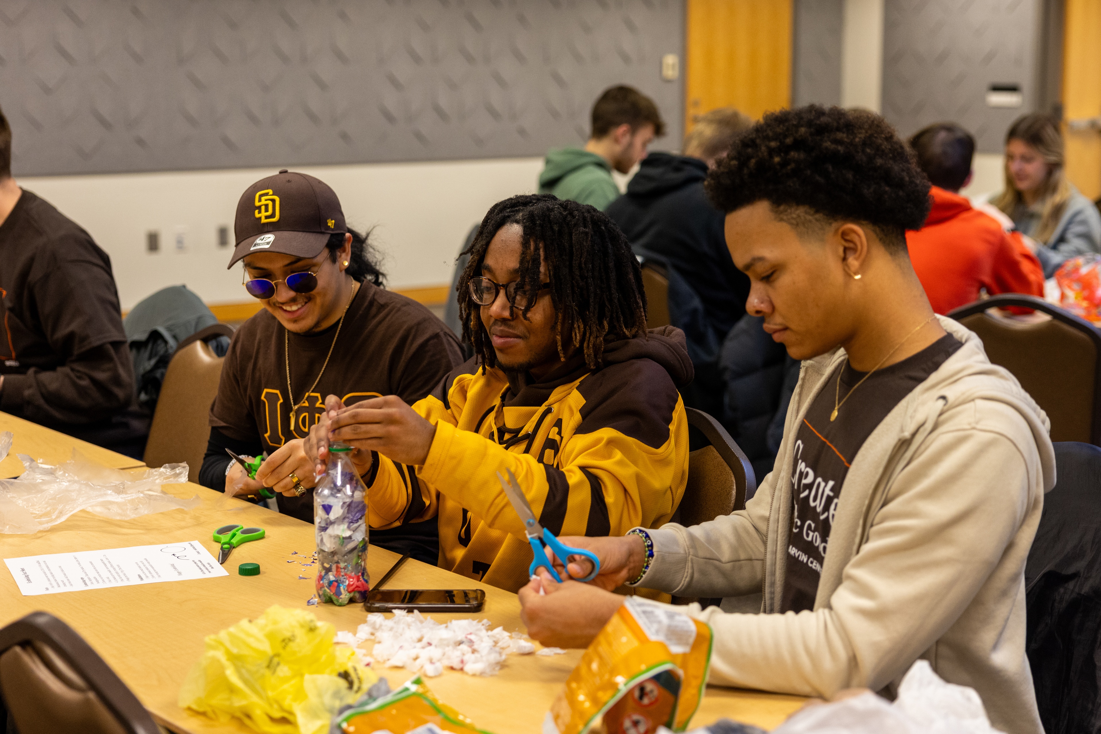 BGSU students cut plastic and pack the tiny pieces into a plastic bottle. 