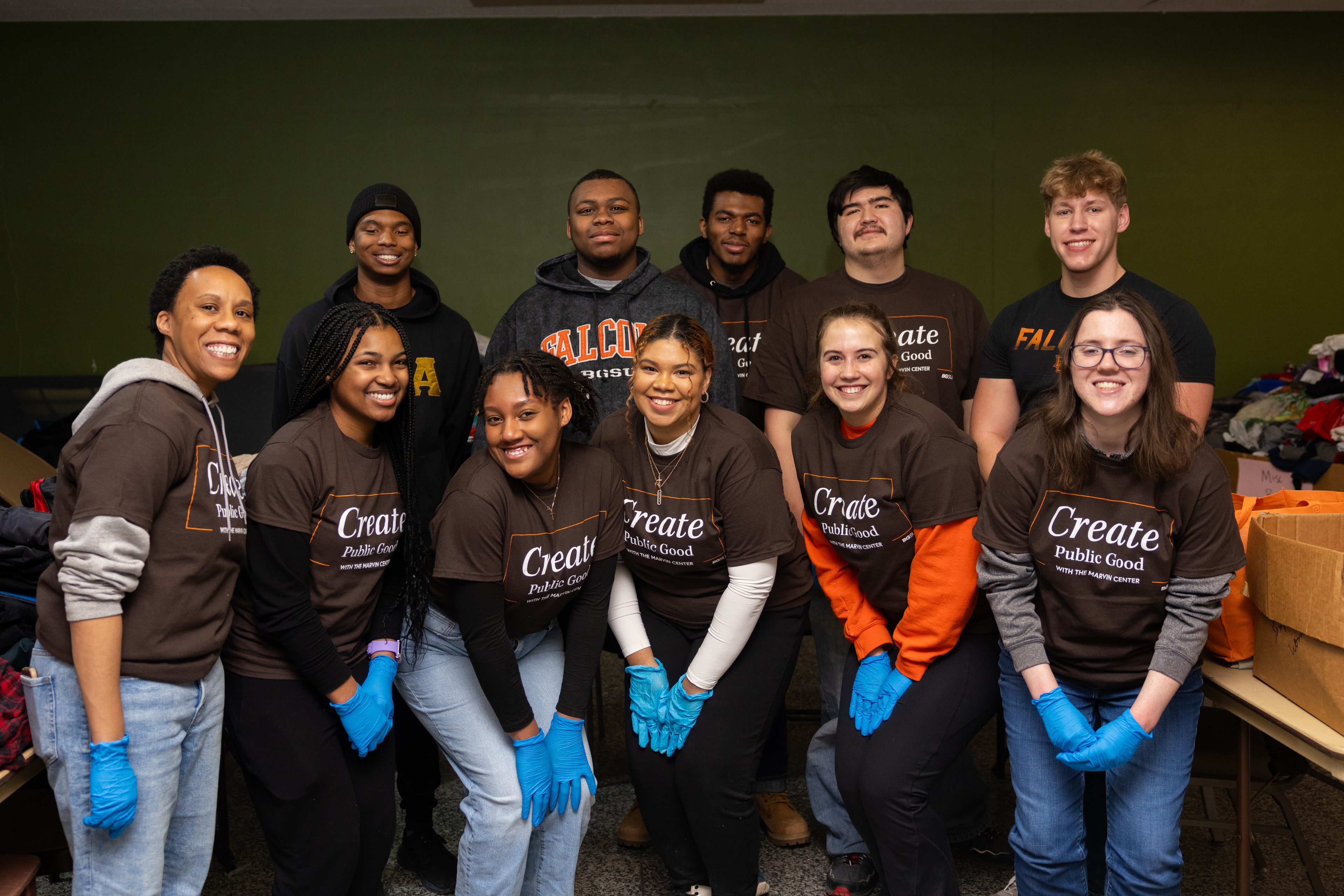 A group of BGSU students and staff wearing shirts that say 'Create public good' pose for a photo. 