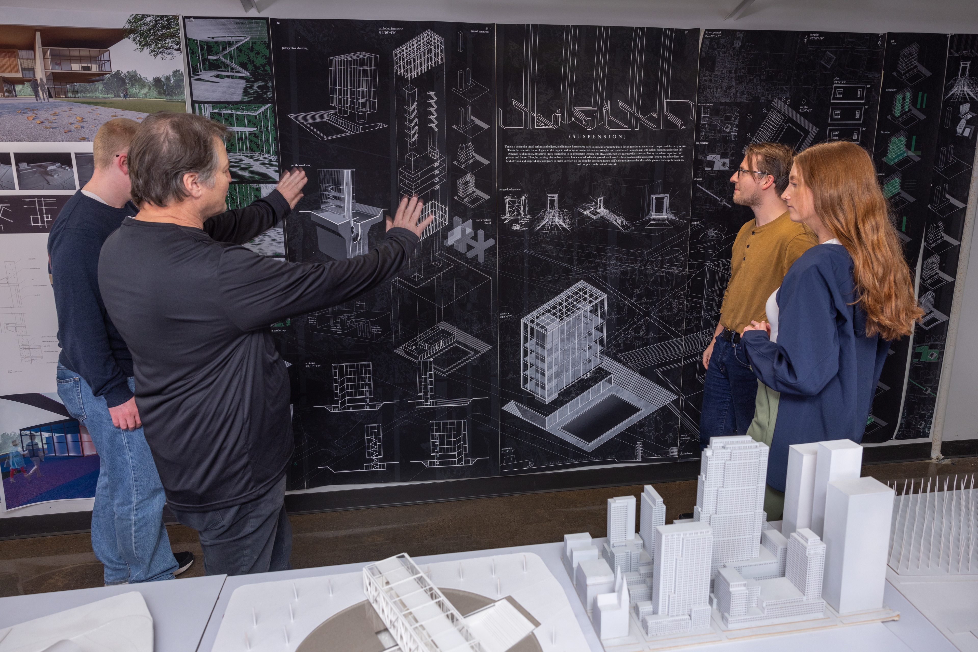 Dr. Andreas Luescher instructs students in front of design plans about suspension of a building.