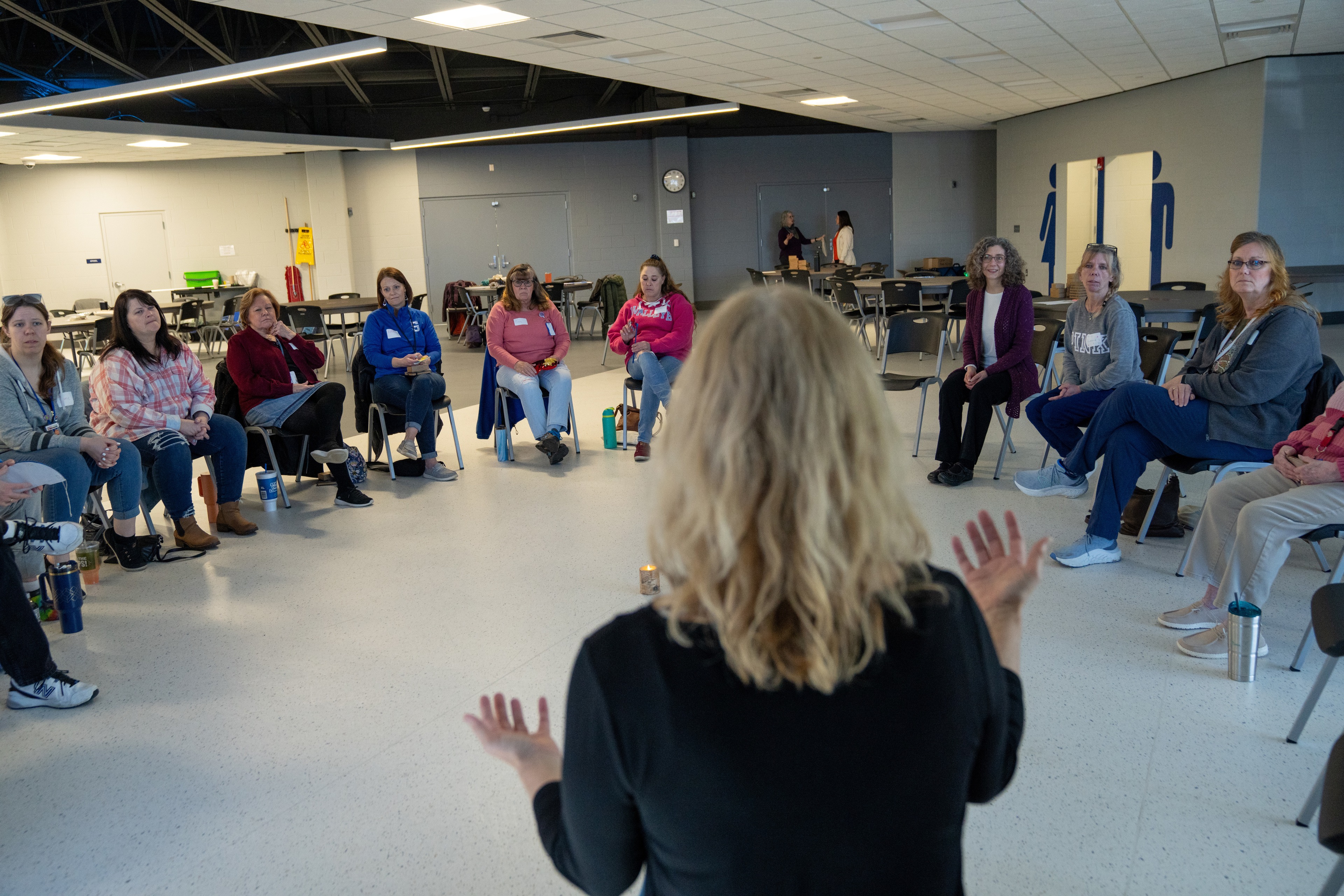 A person addresses a group of people sitting in a circle.