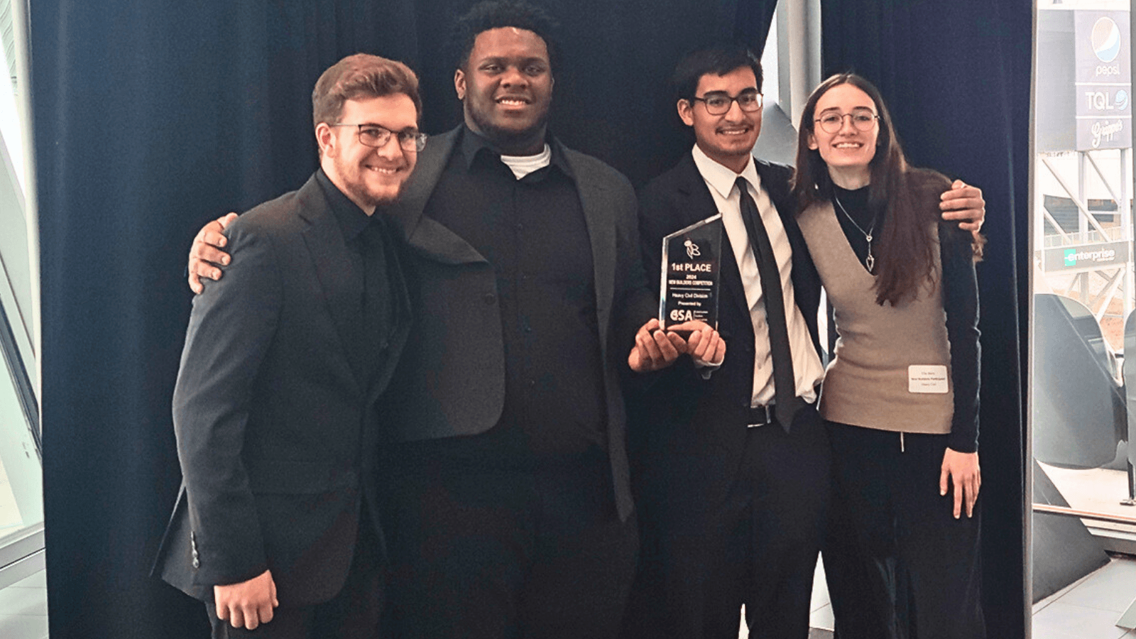 Four people hold a first place trophy