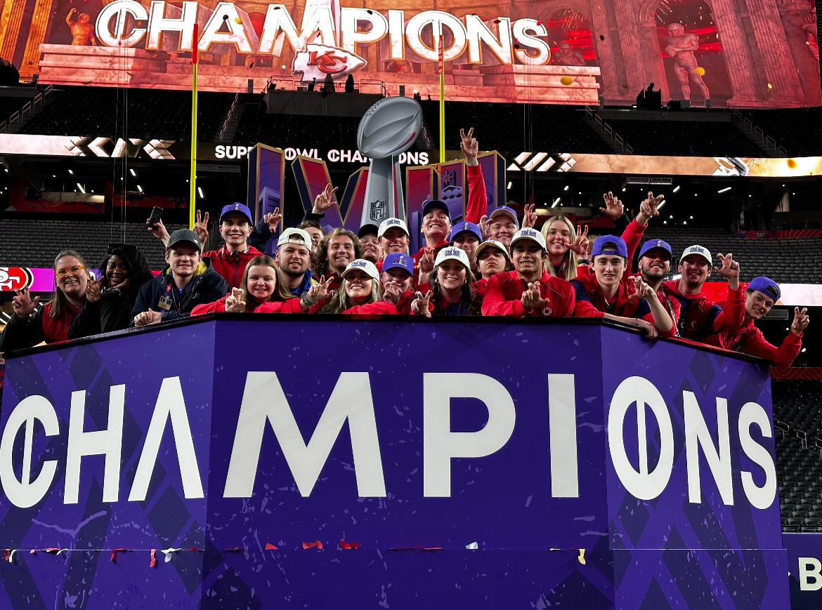 BGSU students stand atop a podium that reads "Champions" after Super Bowl LVIII in Las Vegas.