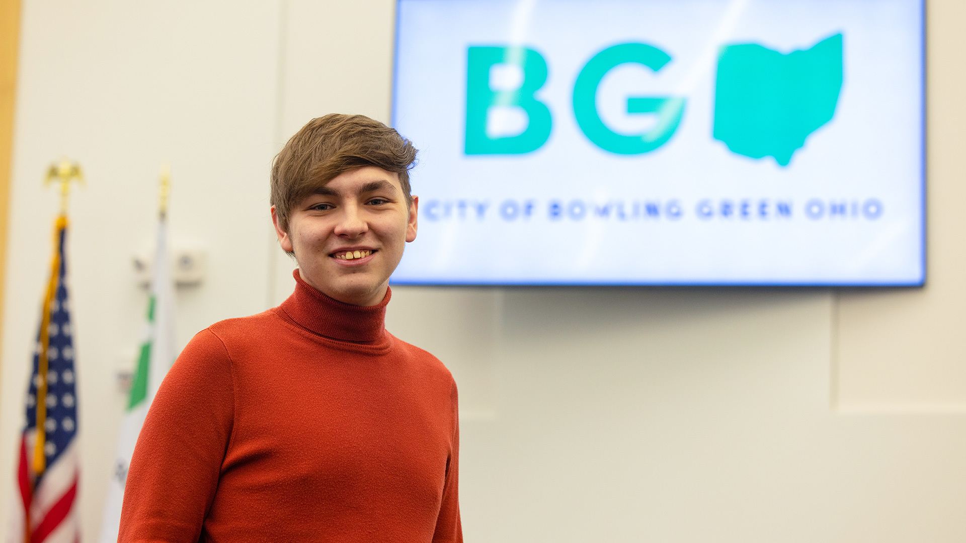 A person standing in front of a City of Bowling Green, Ohio sign.