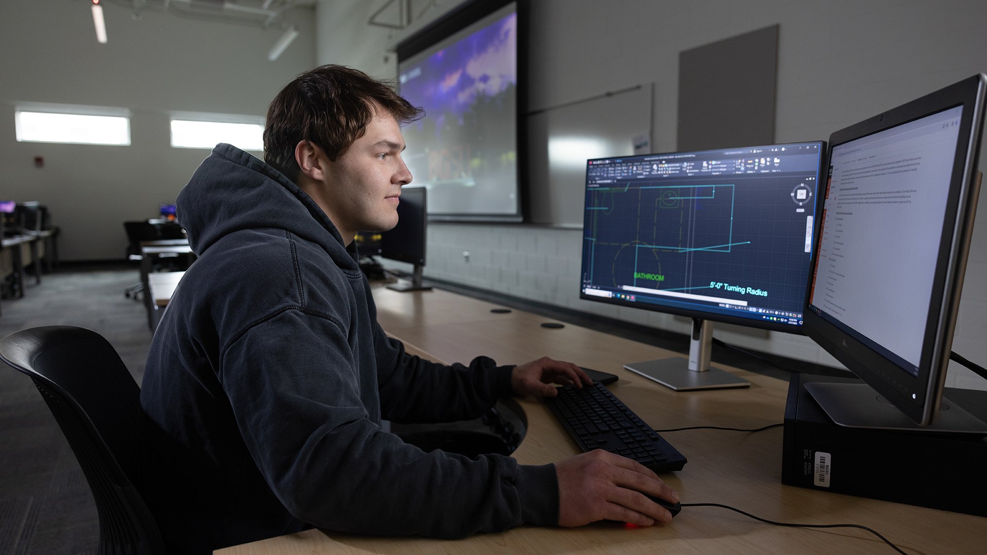 A person works on a computer in a classroom.