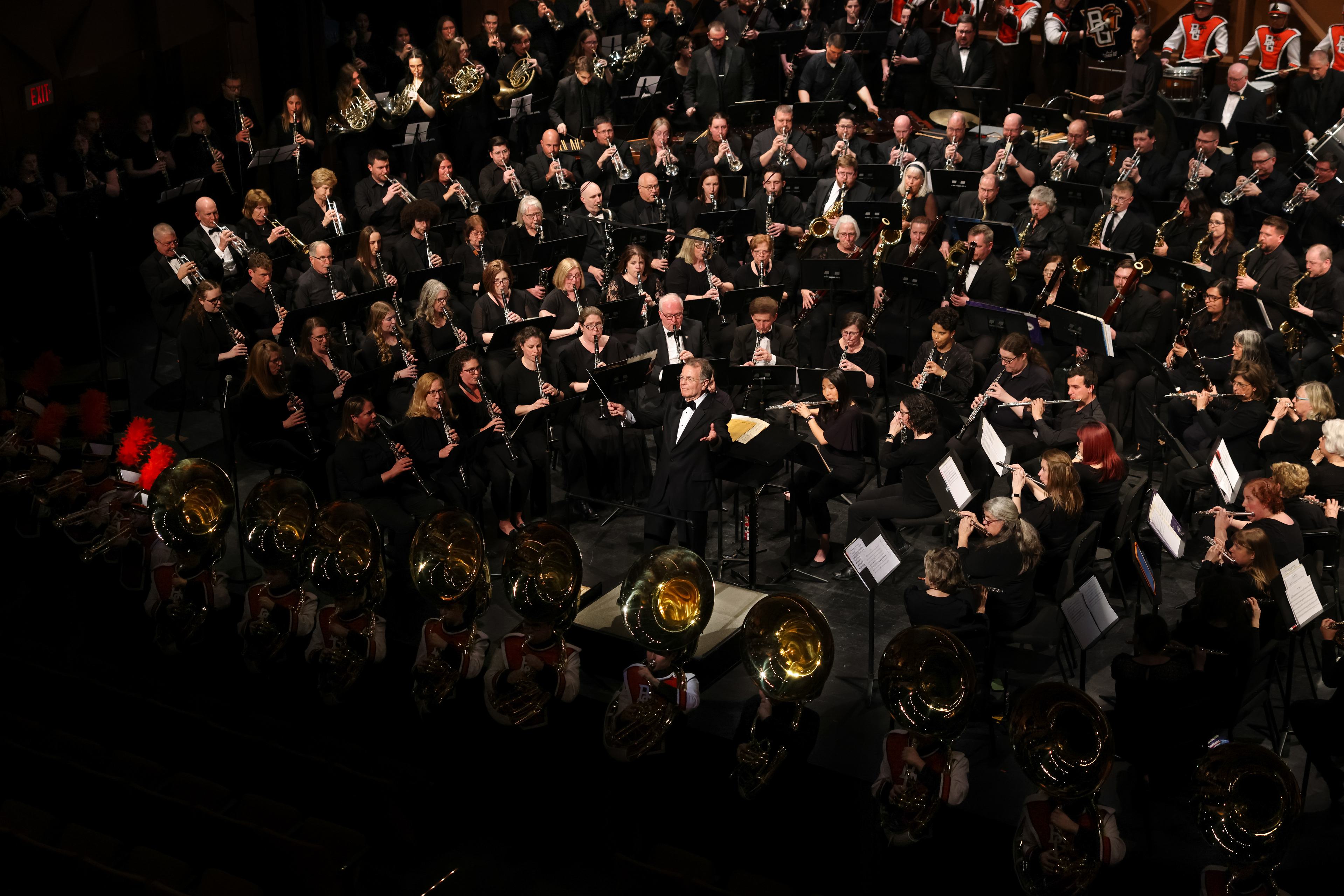 Dr. Bruce Moss holds his baton and faces the audience while the band plays on stage